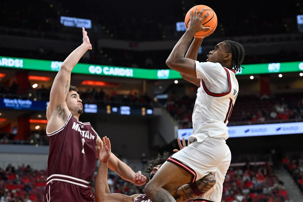 Dec 20, 2025; Louisville, Kentucky, USA; Louisville Cardinals guard Adrian Wooley (14) shoots against Montana Grizzlies forward Trae Taylor (1) and guard Brooklyn Hicks (3) during the second half at KFC Yum! Center. Louisville defeated Montana 94-54. Mandatory Credit: Jamie Rhodes-Imagn Images
