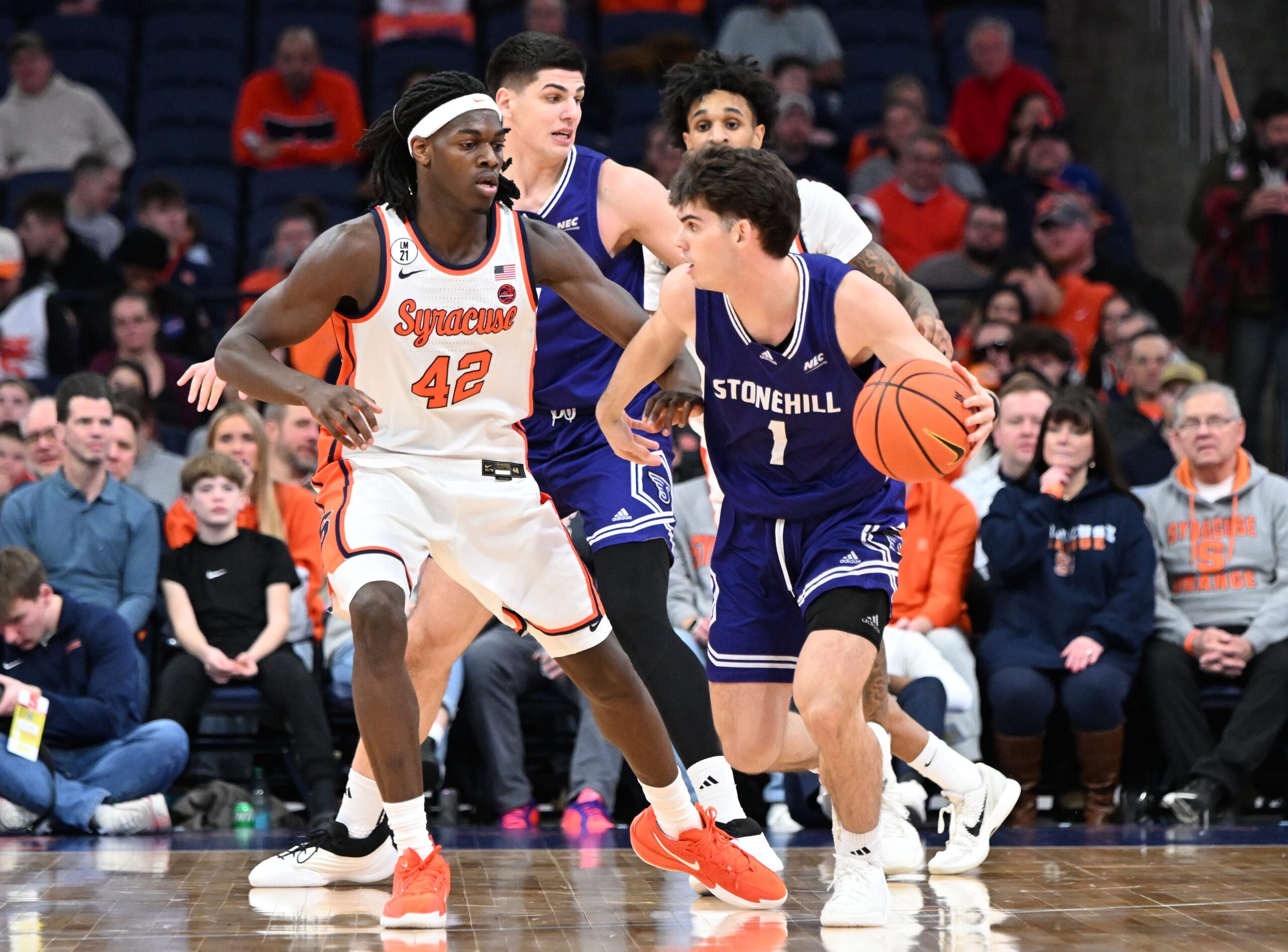 Dec 22, 2025; Syracuse, New York, USA; Stonehill Skyhawks guard Rex Sunderland (1) is defended by Syracuse Orange forward William Kyle III (42) in the second half at the JMA Wireless Dome. Mandatory Credit: Mark Konezny-Imagn Images