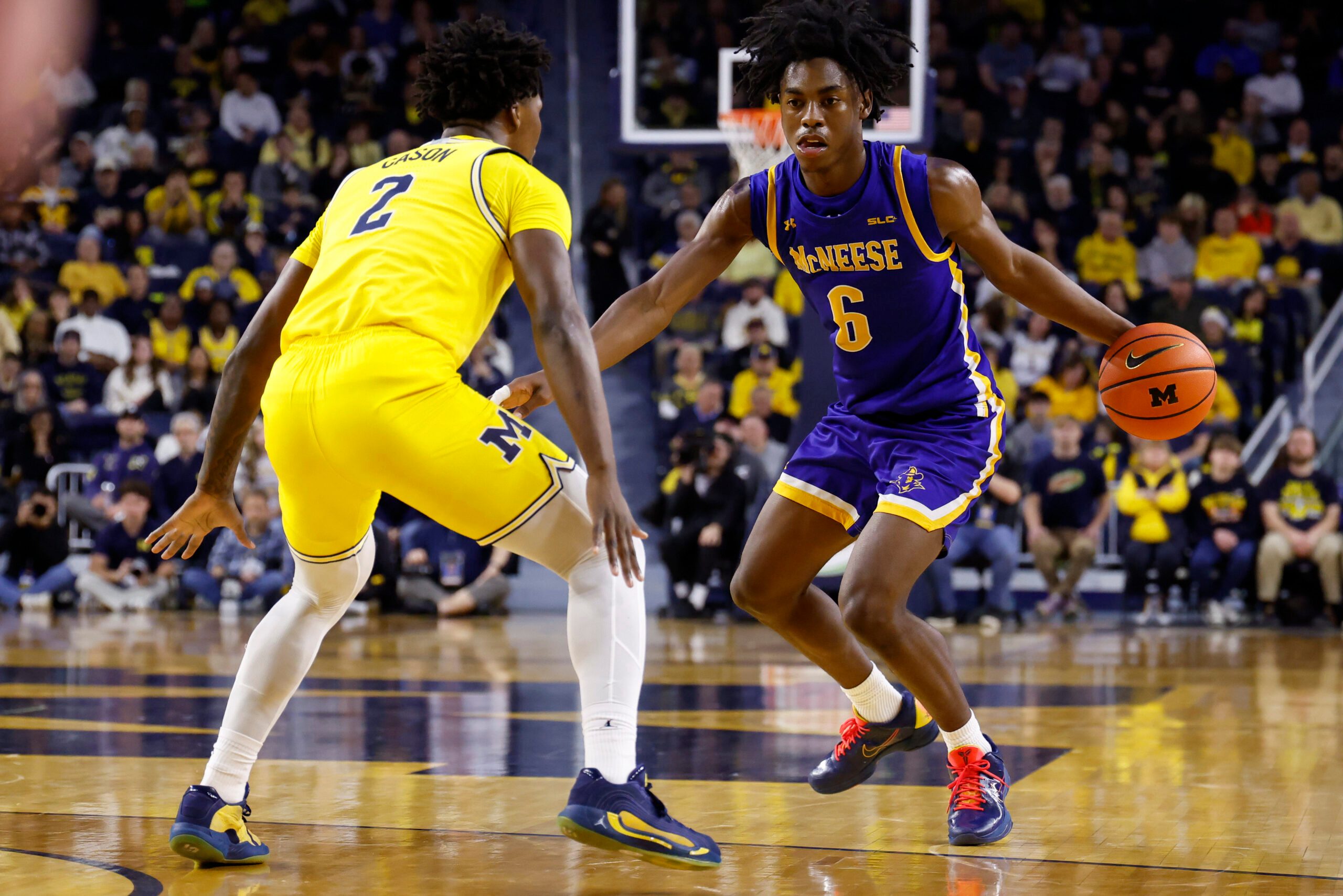 Dec 29, 2025; Ann Arbor, Michigan, USA;  McNeese Cowboys guard Larry Johnson (6) dribbles defended by Michigan Wolverines guard L.J. Cason (2) in the second half at Crisler Center. Mandatory Credit: Rick Osentoski-Imagn Images