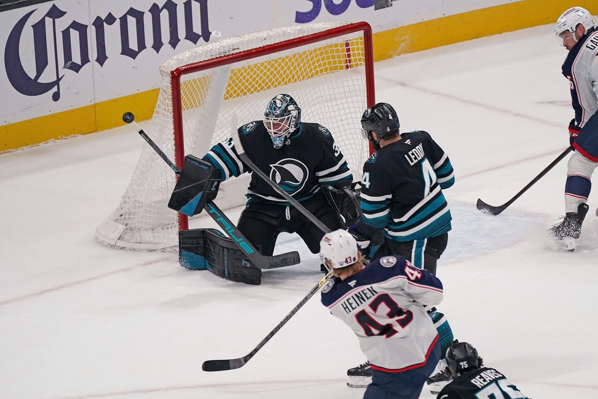 Jan 6, 2026; San Jose, California, USA;  San Jose Sharks goaltender Alex Nedeljkovic (33) makes a save against Columbus Blue Jackets left winger Danton Heinen (43) as San Jose Sharks defenseman Nick Leddy (4) helps defend in the third period at SAP Center at San Jose. Mandatory Credit: David Gonzales-Imagn Images