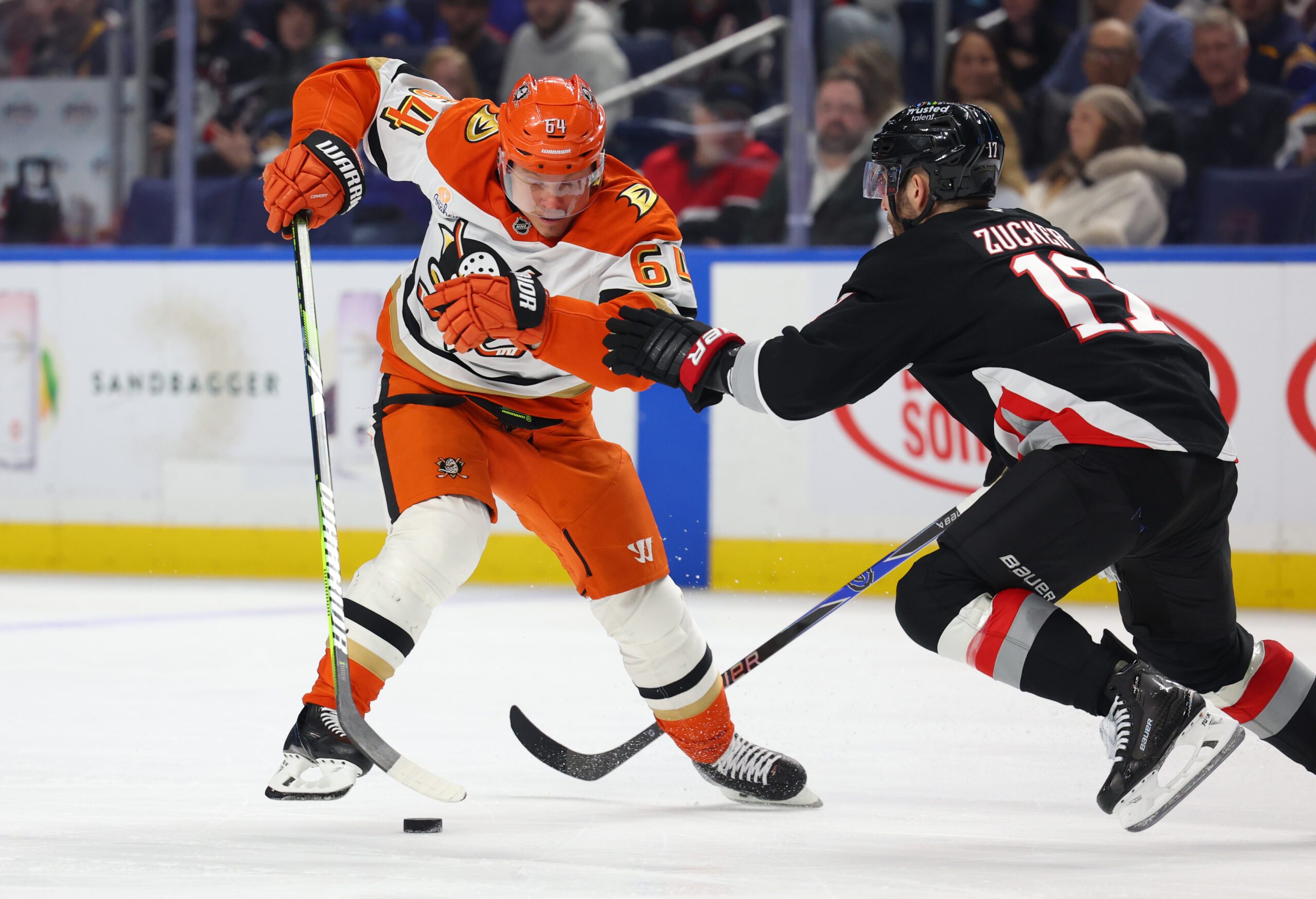 Jan 10, 2026; Buffalo, New York, USA;  Anaheim Ducks center Mikael Granlund (64) looks to control the puck as Buffalo Sabres left wing Jason Zucker (17) defends during the third period at KeyBank Center. Mandatory Credit: Timothy T. Ludwig-Imagn Images