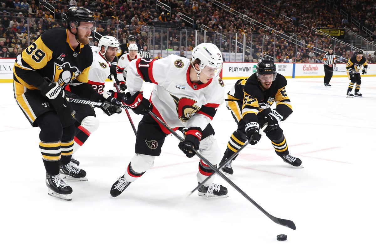 Feb 2, 2026; Pittsburgh, Pennsylvania, USA;  Ottawa Senators center Ridly Greig (71) clears the puck against Pittsburgh Penguins right wing Anthony Mantha (39) and right wing Rickard Rakell (67) during the third period at PPG Paints Arena. Mandatory Credit: Charles LeClaire-Imagn Images