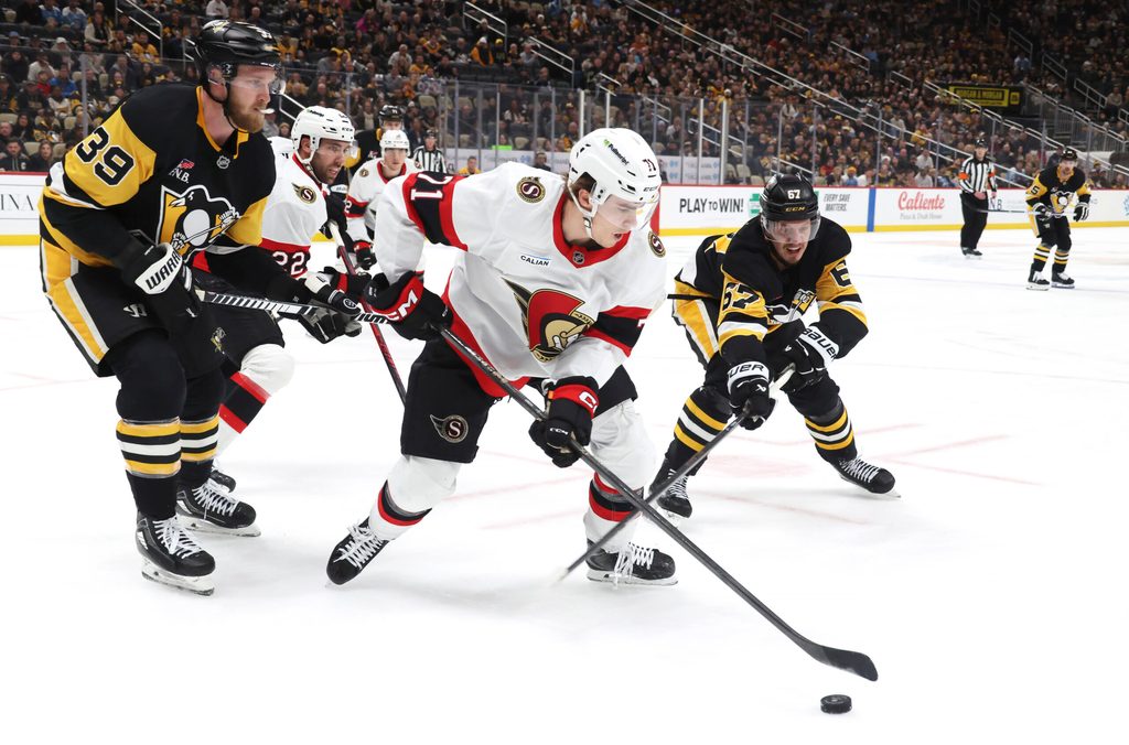 Feb 2, 2026; Pittsburgh, Pennsylvania, USA; Ottawa Senators center Ridly Greig (71) clears the puck against Pittsburgh Penguins right wing Anthony Mantha (39) and right wing Rickard Rakell (67) during the third period at PPG Paints Arena. Mandatory Credit: Charles LeClaire-Imagn Images