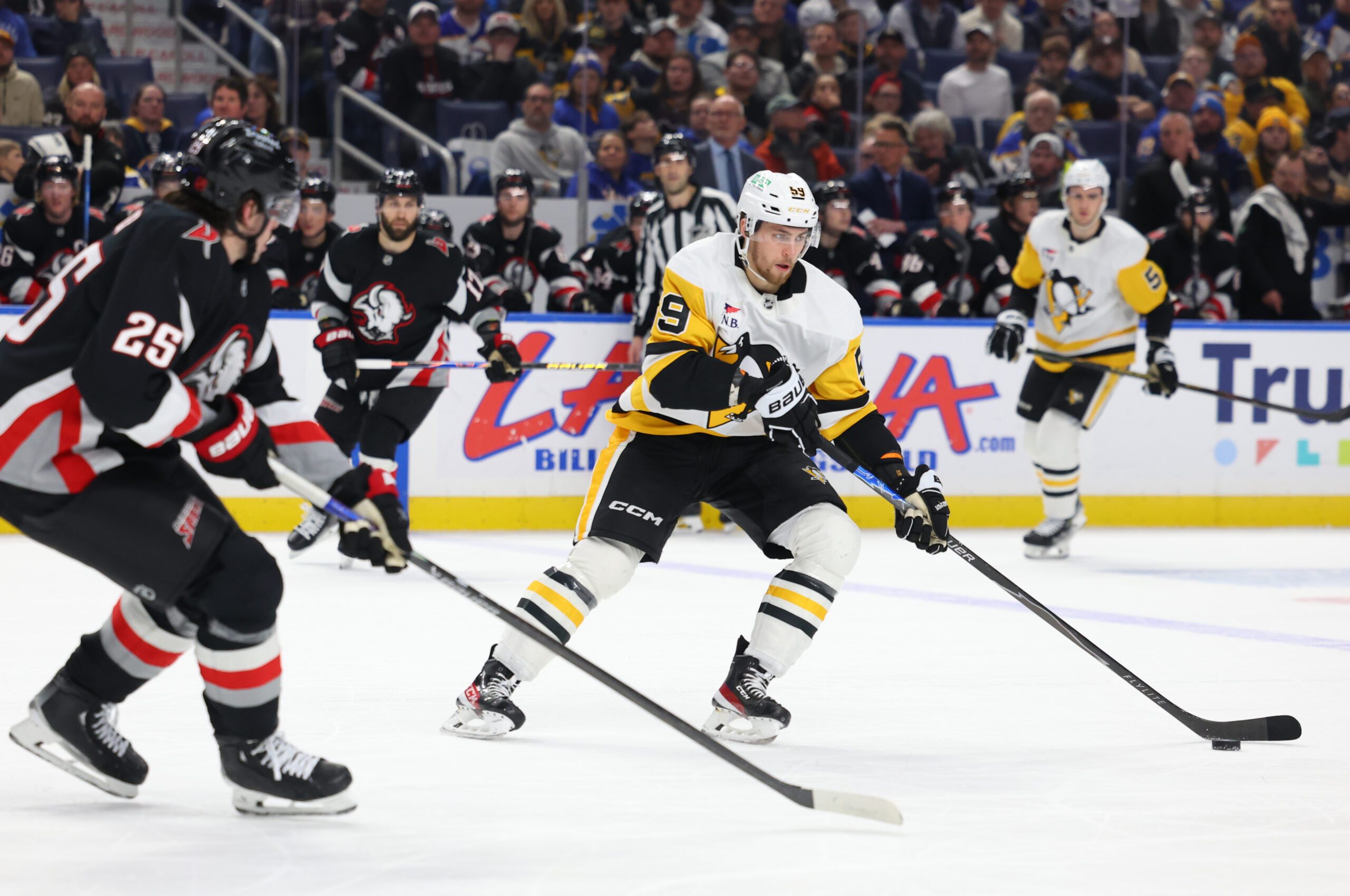 Feb 5, 2026; Buffalo, New York, USA;  Pittsburgh Penguins right wing Egor Chinakhov (59) carries the puck as Buffalo Sabres defenseman Owen Power (25) defends during the third period at KeyBank Center. Mandatory Credit: Timothy T. Ludwig-Imagn Images