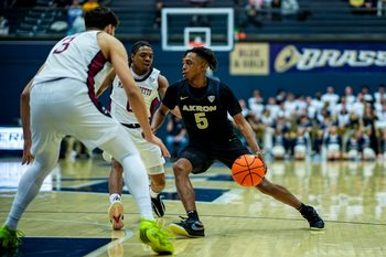 Akron Zips’ Tavari Johnson (5) dribbles around UMass’s Danny Carbuccia (0) and UMass’s Leonardo Bettiol (3), Feb. 13, 2026, at James A Rhodes Arena in Akron, Ohio.
