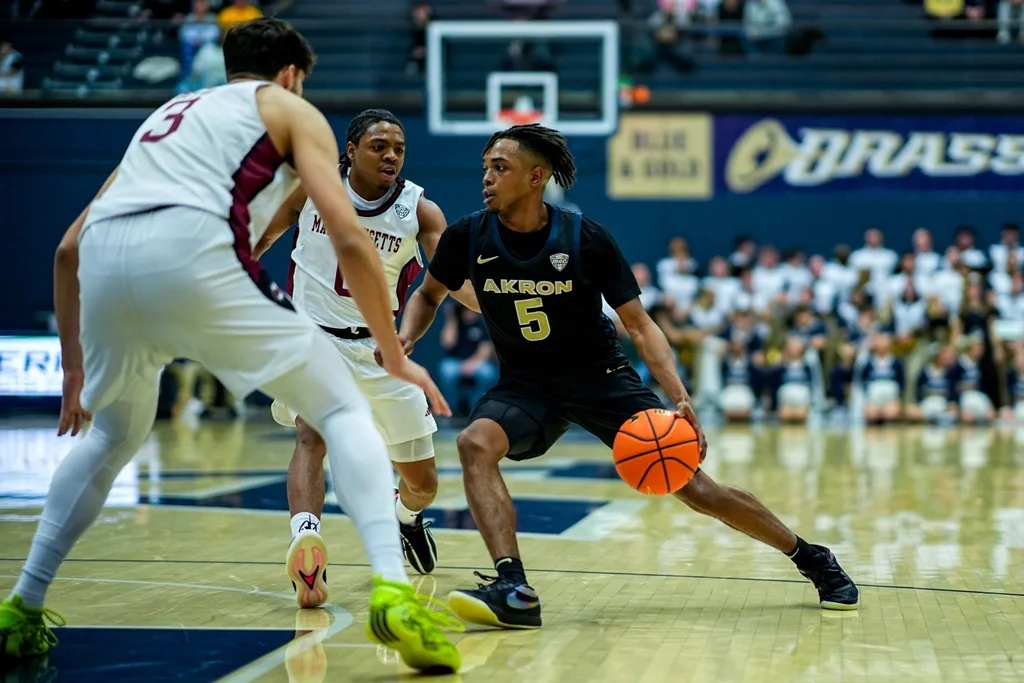 Akron Zips’ Tavari Johnson (5) dribbles around UMass’s Danny Carbuccia (0) and UMass’s Leonardo Bettiol (3), Feb. 13, 2026, at James A Rhodes Arena in Akron, Ohio.