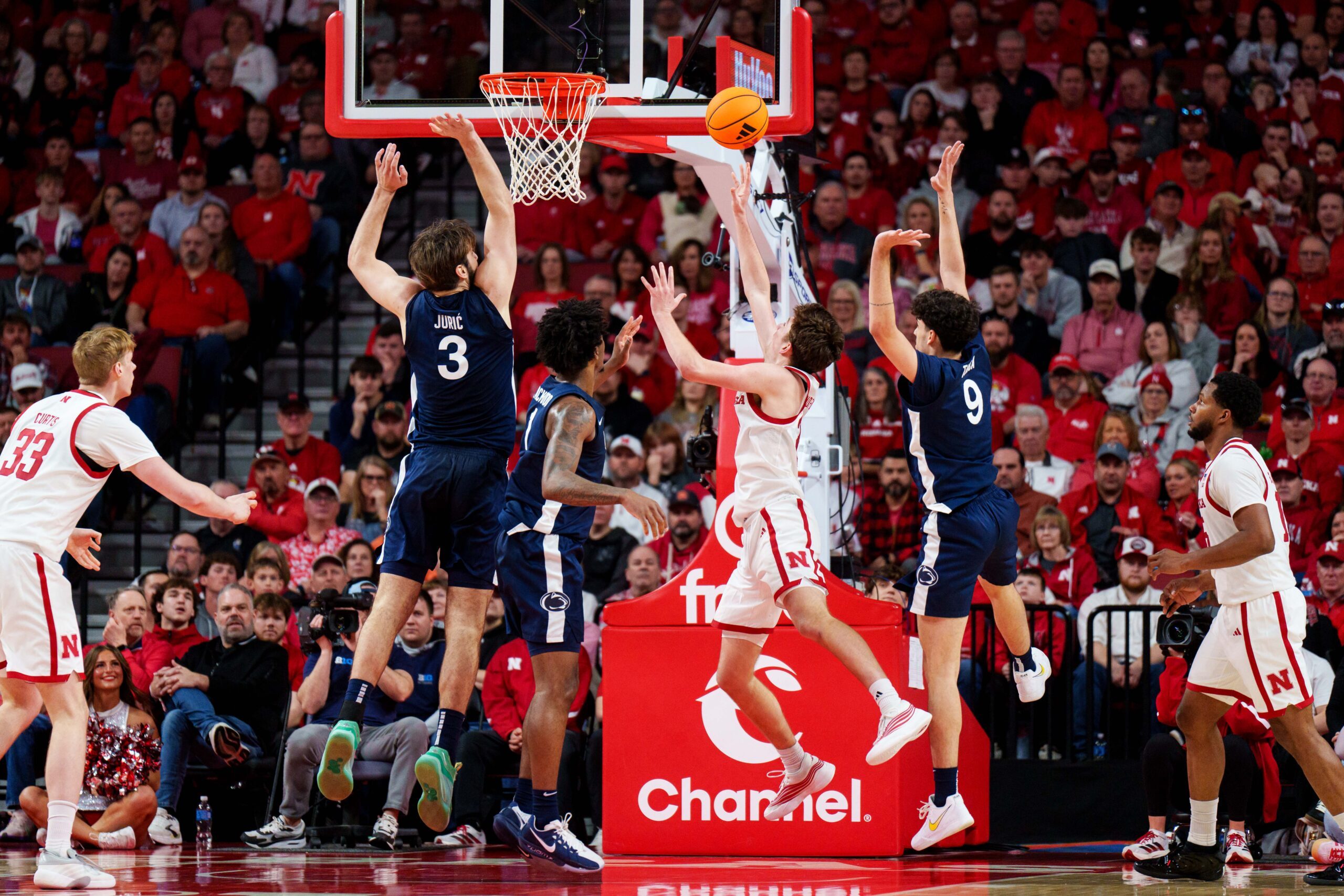 Feb 21, 2026; Lincoln, Nebraska, USA; Nebraska Cornhuskers forward Pryce Sandfort (21) shoots the ball against Penn State Nittany Lions forward Ivan Juric (3), forward Mason Blackwood (1) and guard Melih Tunca (9) during the second half at Pinnacle Bank Arena. Mandatory Credit: Dylan Widger-Imagn Images