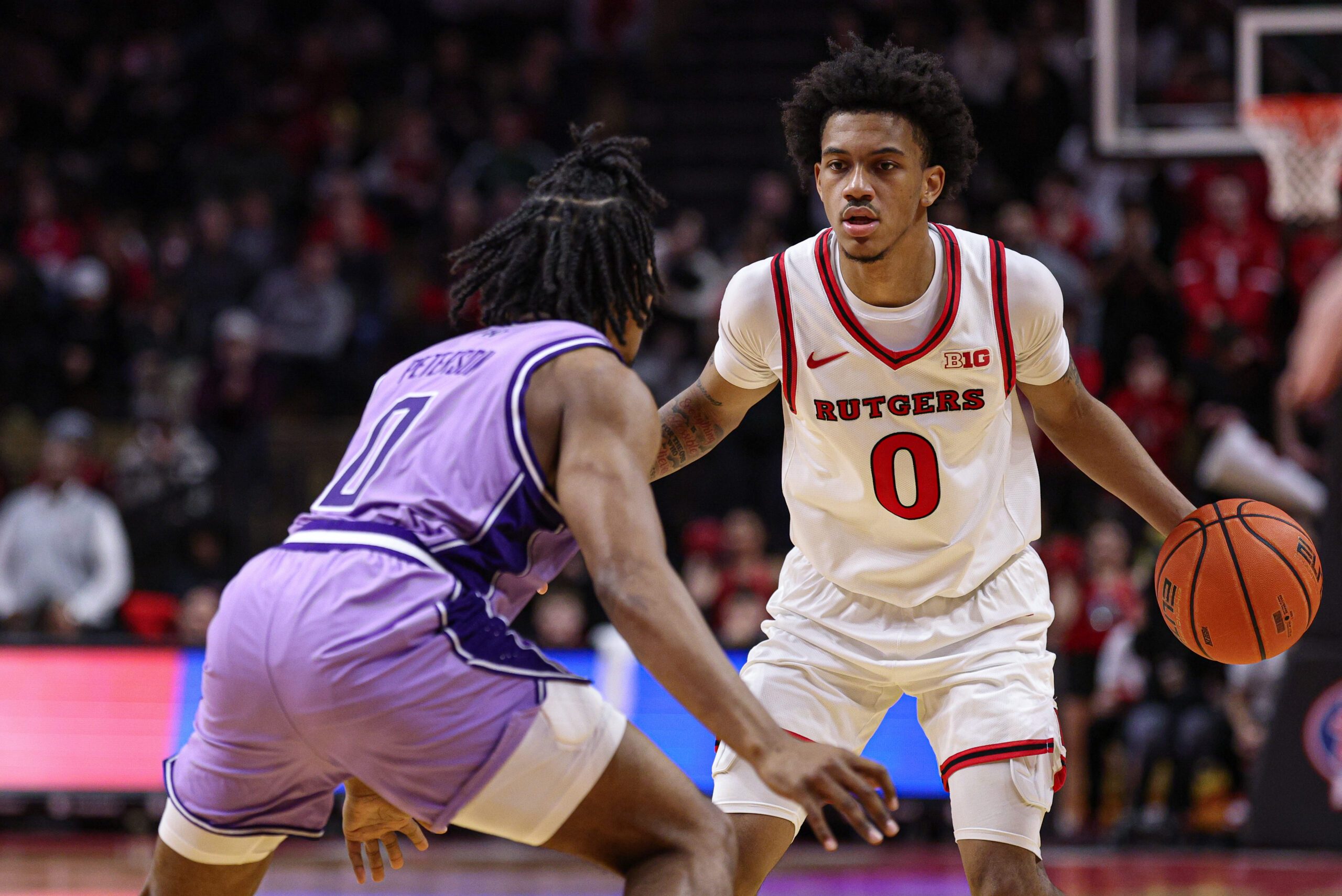 Feb 24, 2026; Piscataway, New Jersey, USA; Rutgers Scarlet Knights guard Tariq Francis (0) is guarded by Washington Huskies guard Quimari Peterson (0) during the second half at Jersey Mike's Arena. Mandatory Credit: Vincent Carchietta-Imagn Images