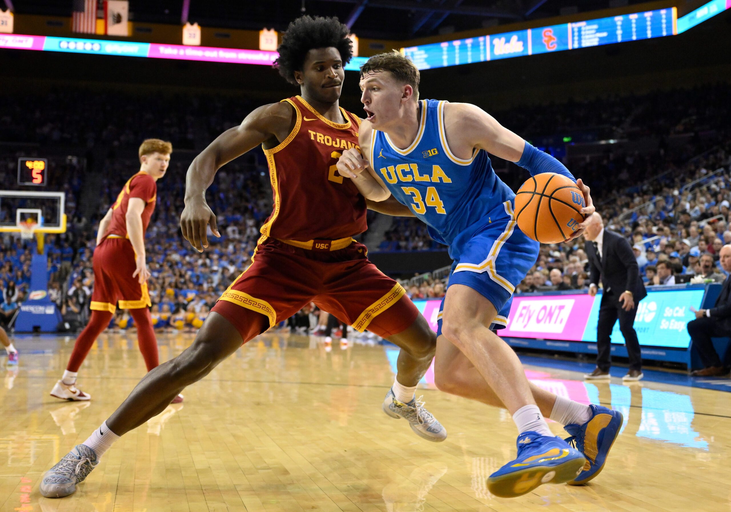 Feb 24, 2026; Los Angeles, California, USA; UCLA Bruins forward Tyler Bilodeau (34) drives to the basket defended by Southern California Trojans forward Ezra Ausar (2) during the second half at Pauley Pavilion presented by Wescom Financial. Mandatory Credit: Robert Hanashiro-Imagn Images