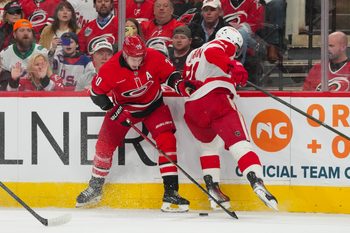 Feb 28, 2026; Raleigh, North Carolina, USA;  Carolina Hurricanes center Sebastian Aho (20) and Detroit Red Wings center Dylan Larkin (71) battle over the puck during the first period at Lenovo Center. Mandatory Credit: James Guillory-Imagn Images