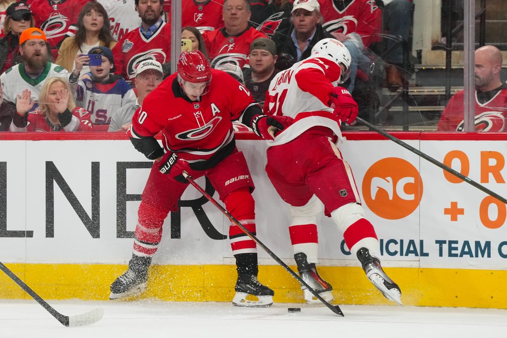 Feb 28, 2026; Raleigh, North Carolina, USA; Carolina Hurricanes center Sebastian Aho (20) and Detroit Red Wings center Dylan Larkin (71) battle over the puck during the first period at Lenovo Center. Mandatory Credit: James Guillory-Imagn Images