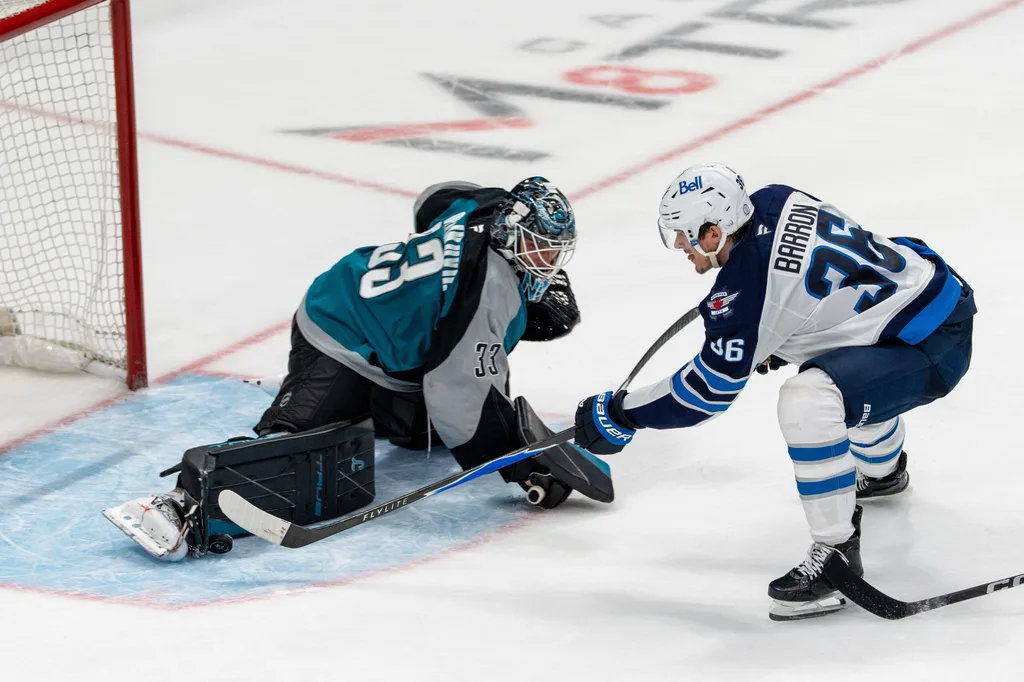 March 1, 2026; San Jose, California, USA; San Jose Sharks goaltender Alex Nedeljkovic (33) blocks the shot of Winnipeg Jets center Morgan Barron (36) during the third period at SAP Center at San Jose. Mandatory Credit: Neville E. Guard-Imagn Images