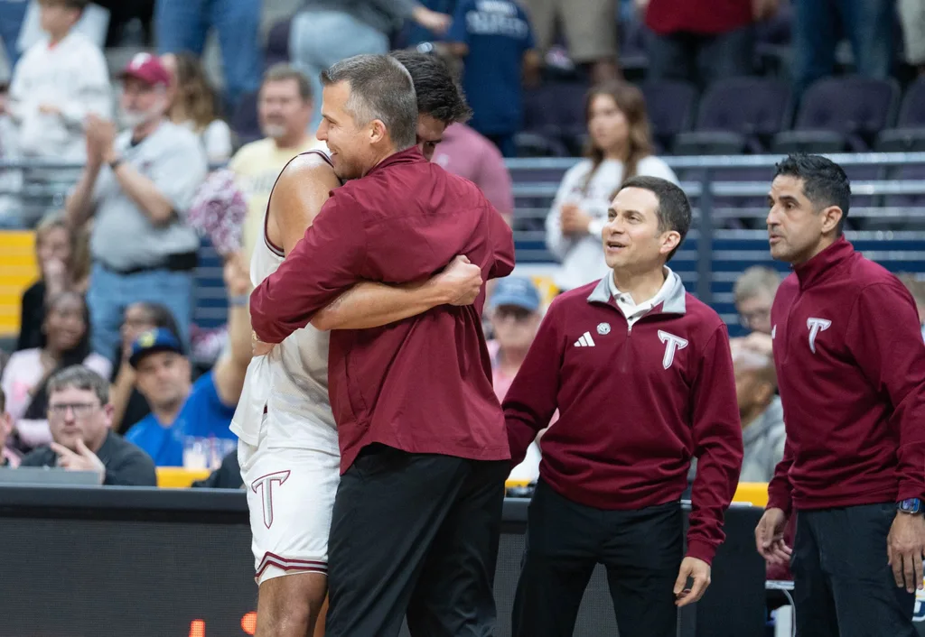 Trojans Victor Valdes (11) and head coach Scott Cross embrace as time runs down in their 77-61 victory over the Eagles during the Georgia Southern vs Troy men’s Sun Belt Conference Championship basketball game at the Pensacola Bay Center in Pensacola, Florida on March 9, 2026.