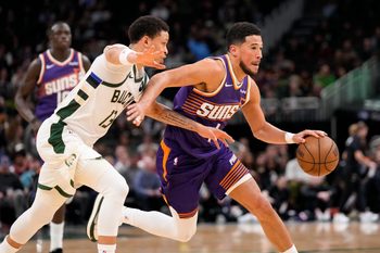 Mar 10, 2026; Milwaukee, Wisconsin, USA;  Phoenix Suns guard Devin Booker (1) drives towards the basket against Milwaukee Bucks guard Ryan Rollins (13) during the third quarter at Fiserv Forum. Mandatory Credit: Jeff Hanisch-Imagn Images