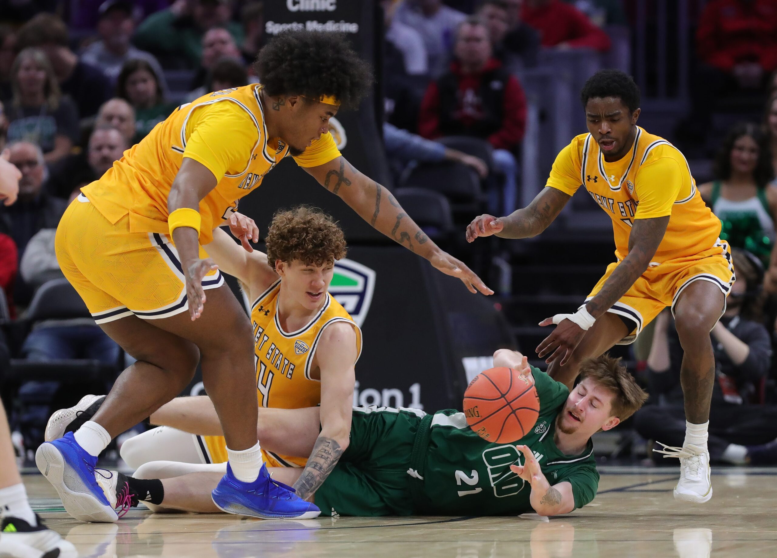 Ohio Bobcats guard Jesse Burris (21) tries to get rid of the ball under pressure from Kent State Golden Flashes guard Rob Whaley Jr. (2), forward Magnus Entenmann (14) and guard Cian Medley (1) during the second half of an NCAA college basketball game in the quarterfinals of the MAC Basketball Tournament at Rocket Arena, March 12, 2026, in Cleveland, Ohio.