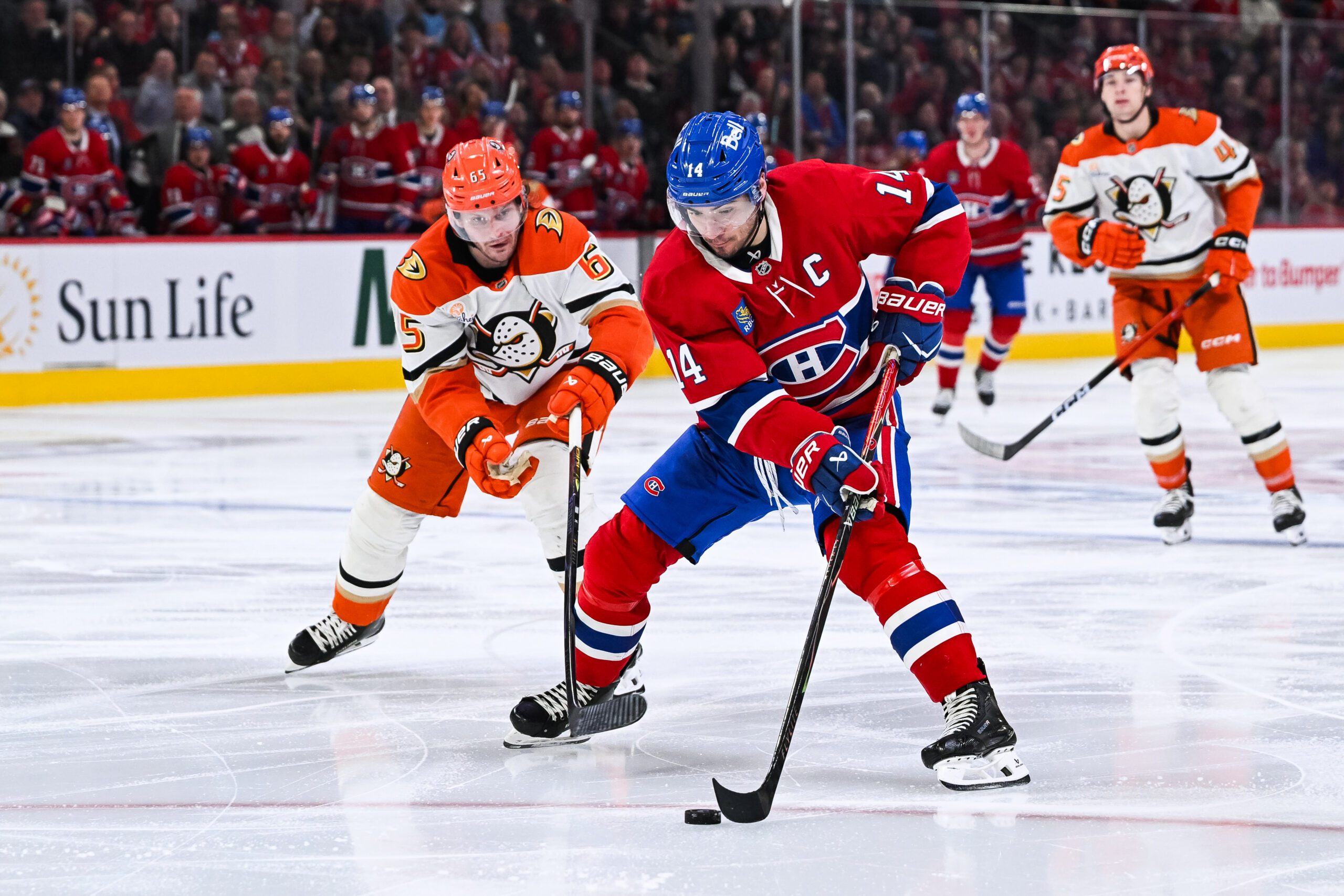Mar 15, 2026; Montreal, Quebec, CAN; Montreal Canadiens center Nick Suzuki (14) plays the puck against Anaheim Ducks defenseman Jacob Trouba (65) during the third period at Bell Centre. Mandatory Credit: David Kirouac-Imagn Images