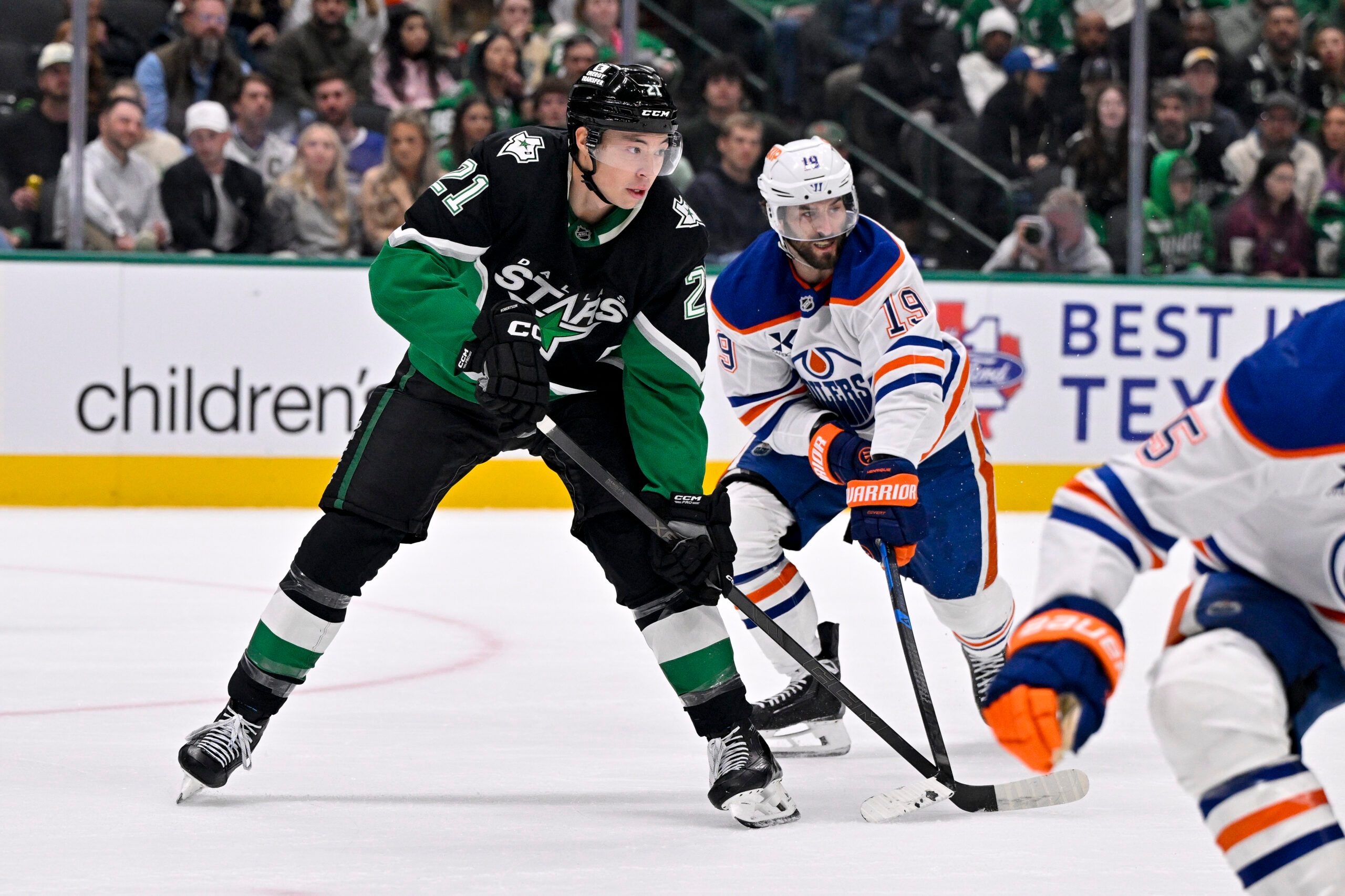 Mar 12, 2026; Dallas, Texas, USA; Dallas Stars left wing Jason Robertson (21) and Edmonton Oilers center Adam Henrique (19) look for the puck during the game between the Stars and the Oilers at the American Airlines Center. Mandatory Credit: Jerome Miron-Imagn Images