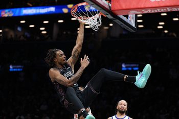 Mar 20, 2026; Brooklyn, New York, USA; Brooklyn Nets center Nic Claxton (33) hangs on the rim after a dunk during the second half against New York Knicks guard Mikal Bridges (25) at Barclays Center. Mandatory Credit: Vincent Carchietta-Imagn Images