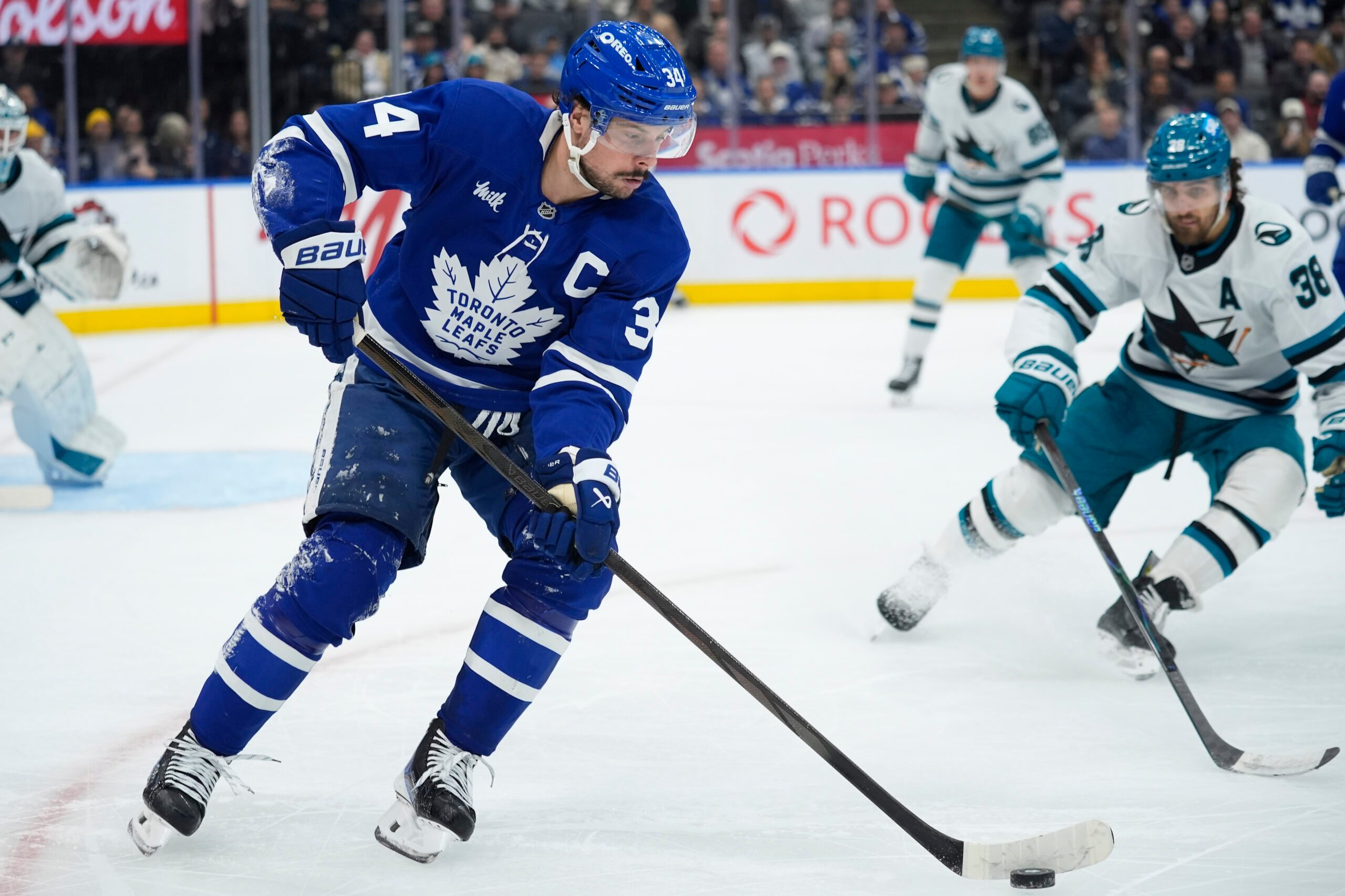 Dec 11, 2025; Toronto, Ontario, CAN; Toronto Maple Leafs forward Auston Matthews (34) controls the puck as San Jose Sharks defenseman Mario Ferraro (38) closes in during the third period at Scotiabank Arena. Mandatory Credit: John E. Sokolowski-Imagn Images