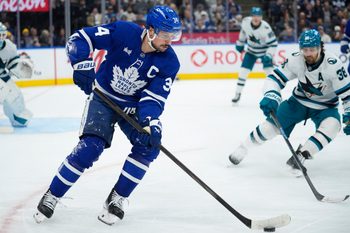Dec 11, 2025; Toronto, Ontario, CAN; Toronto Maple Leafs forward Auston Matthews (34) controls the puck as San Jose Sharks defenseman Mario Ferraro (38) closes in during the third period at Scotiabank Arena. Mandatory Credit: John E. Sokolowski-Imagn Images