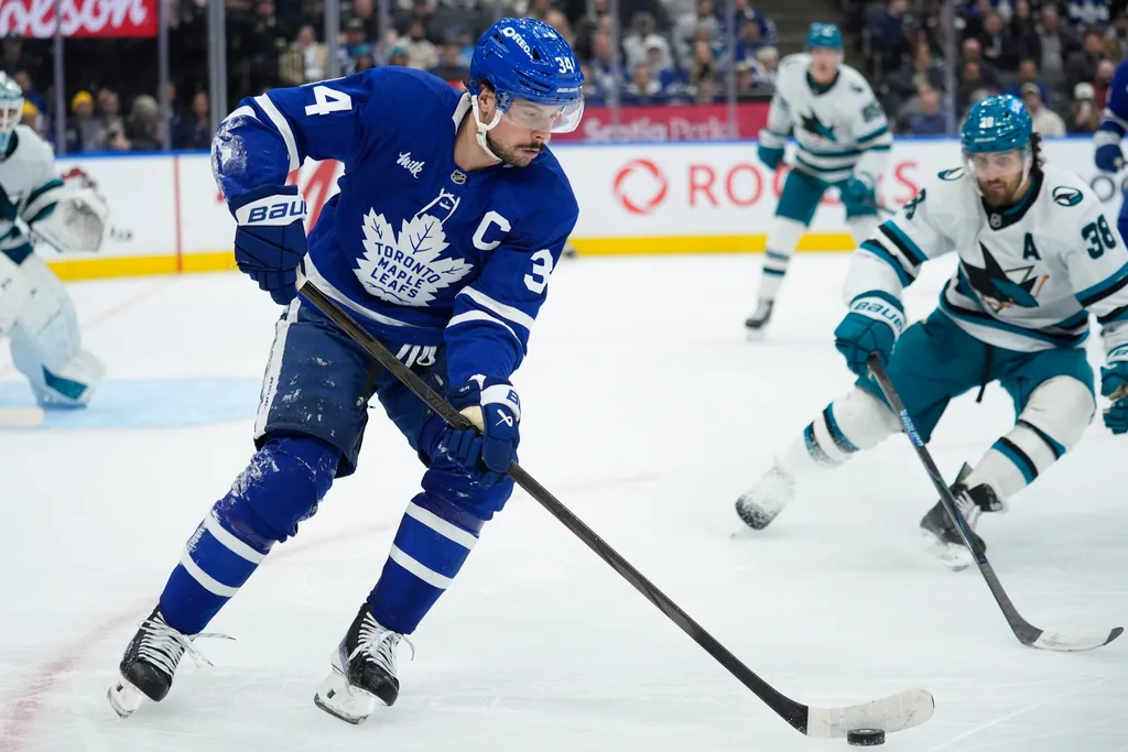Dec 11, 2025; Toronto, Ontario, CAN; Toronto Maple Leafs forward Auston Matthews (34) controls the puck as San Jose Sharks defenseman Mario Ferraro (38) closes in during the third period at Scotiabank Arena. Mandatory Credit: John E. Sokolowski-Imagn Images
