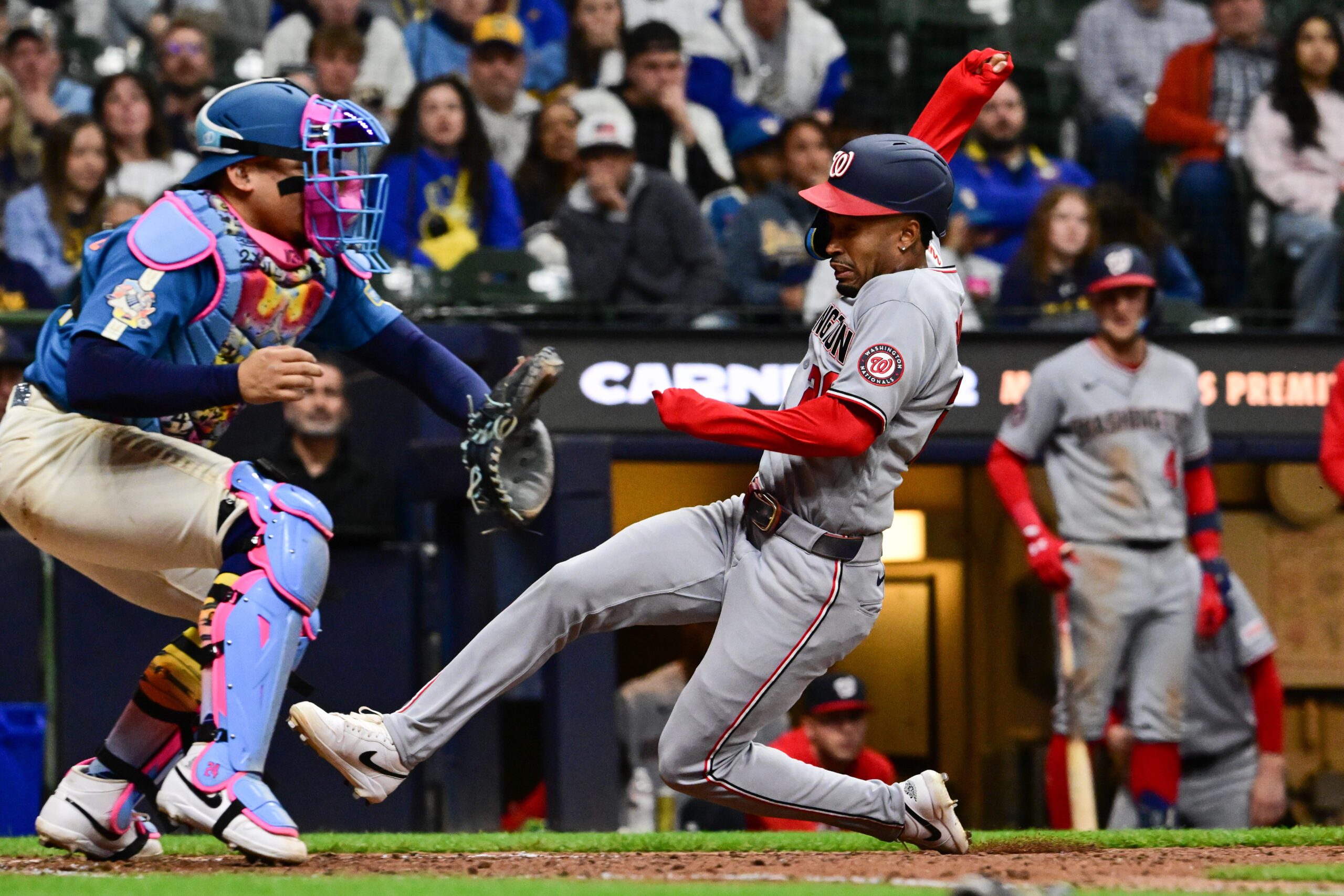 Apr 10, 2026; Milwaukee, Wisconsin, USA; Washington Nationals shortstop Nasim Nunez (26) scores on a squeeze bunt as Milwaukee Brewers catcher William Contreras (24) waits for the ball in the ninth inning at American Family Field. Mandatory Credit: Benny Sieu-Imagn Images