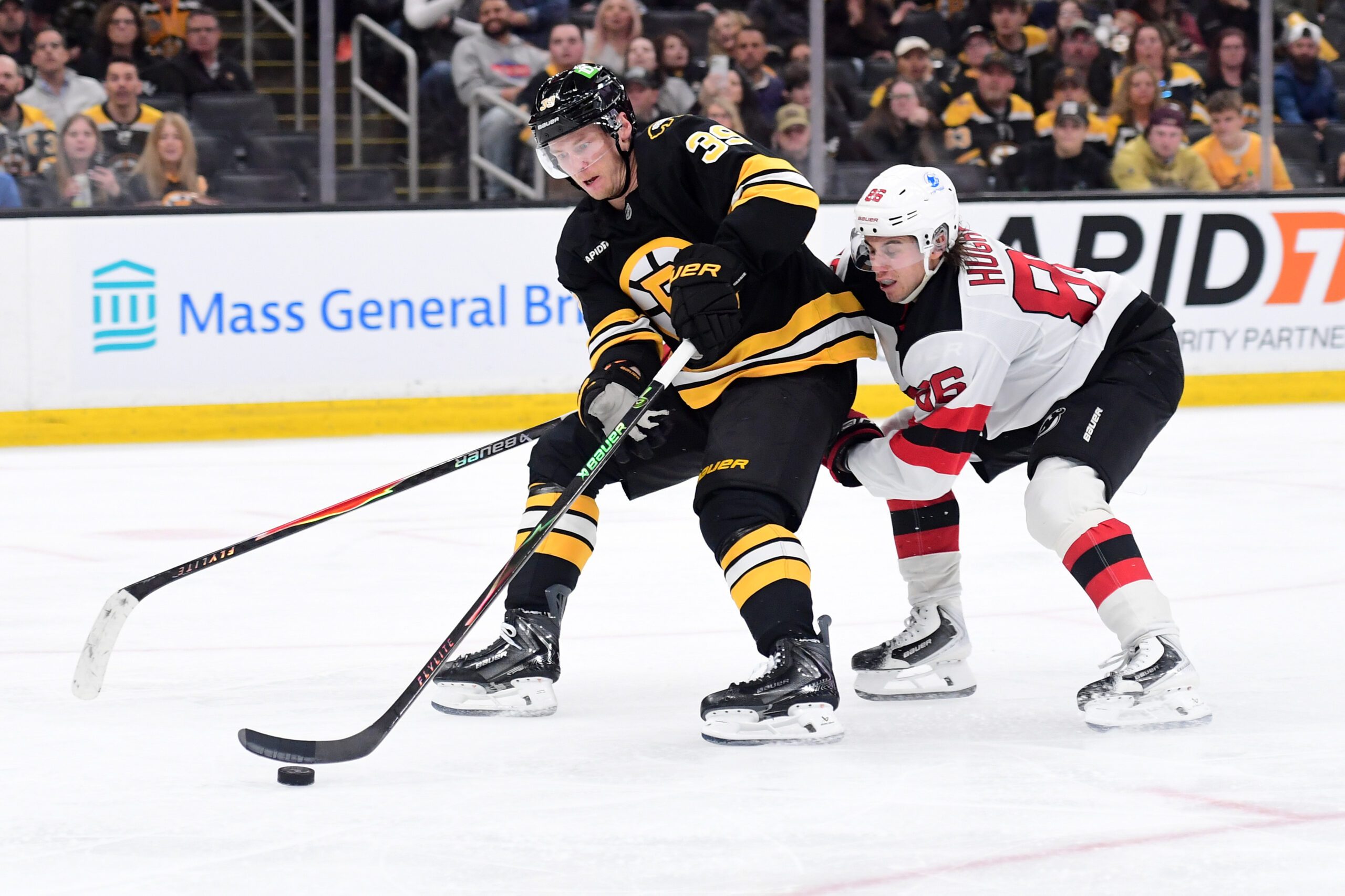 Apr 14, 2026; Boston, Massachusetts, USA; Boston Bruins center Morgan Geekie (39) controls the puck against New Jersey Devils center Jack Hughes (86) during the third period at TD Garden. Mandatory Credit: Bob DeChiara-Imagn Images