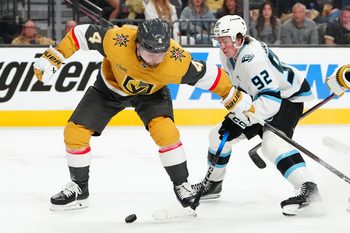 Apr 19, 2026; Las Vegas, Nevada, USA; Utah Mammoth center Logan Cooley (92) slips the puck around Vegas Golden Knights defenseman Rasmus Andersson (4) during the second period of game one of the first round of the 2026 Stanley Cup Playoffs at T-Mobile Arena. Mandatory Credit: Stephen R. Sylvanie-Imagn Images