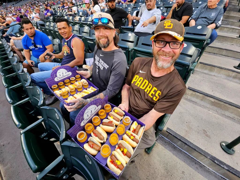 Apr 21, 2026; Denver, Colorado, USA; Colorado Rockies and San Diego Padres fans with the 999 challenge hot dog and beer food during the game at Coors Field. Mandatory Credit: Ron Chenoy-Imagn Images