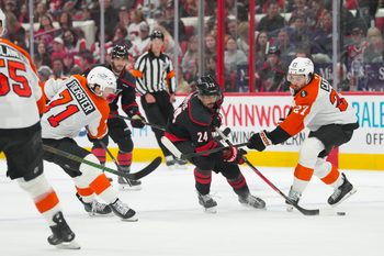 May 2, 2026; Raleigh, North Carolina, USA; Carolina Hurricanes center Seth Jarvis (24) skates with the puck between Philadelphia Flyers left wing Noah Cates (27) and right wing Tyson Foerster (71) during the third period at Lenovo Center. Mandatory Credit: James Guillory-Imagn Images