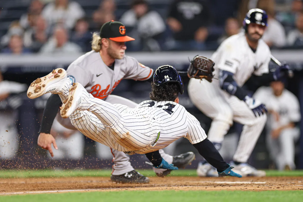 May 4, 2026; Bronx, New York, USA; New York Yankees left fielder Jasson Dominguez (24) scores a run won a wild pitch before being tagged by Baltimore Orioles pitcher Shane Baz (34) during the sixth inning at Yankee Stadium. Mandatory Credit: Vincent Carchietta-Imagn Images