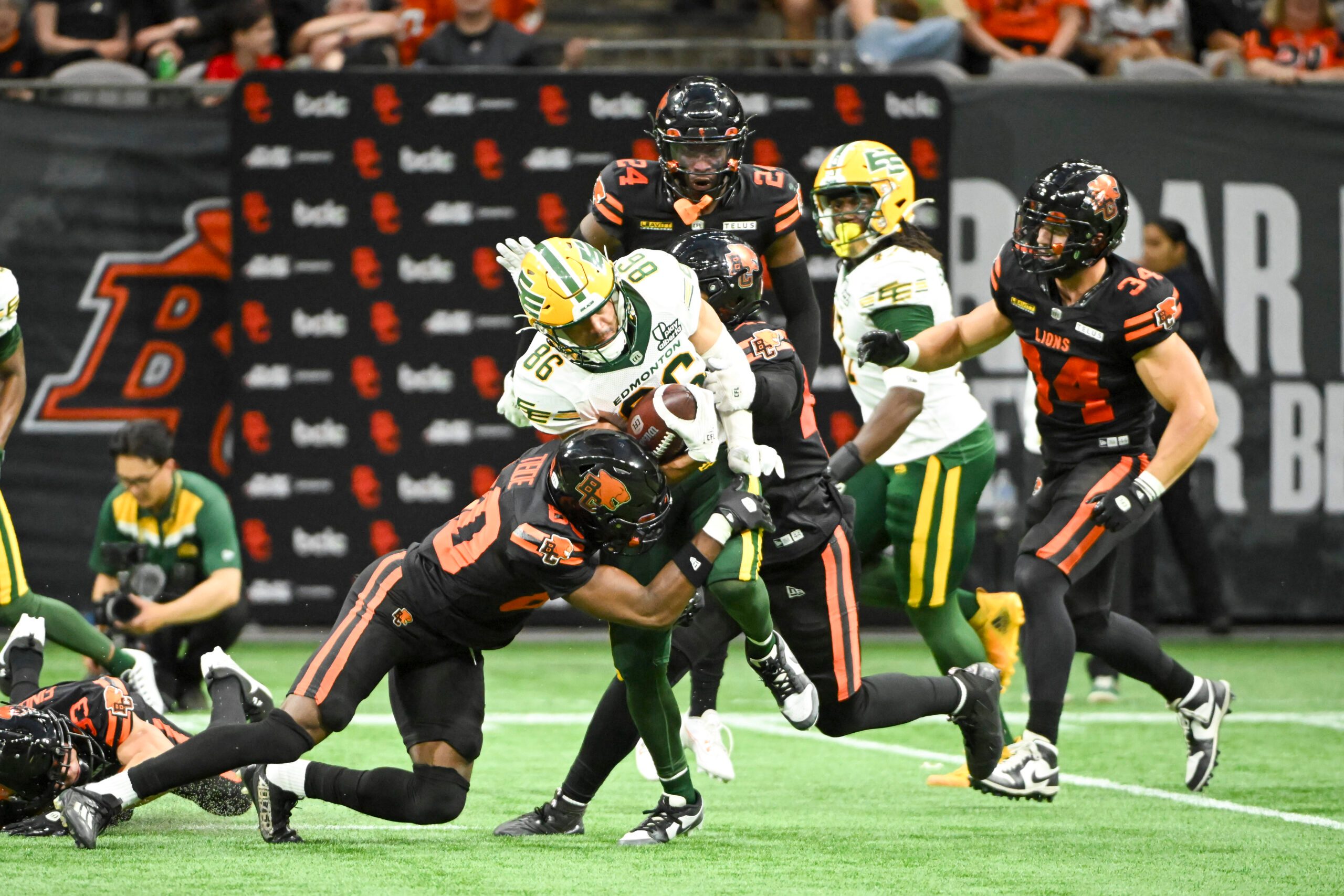 Jun 7, 2025; Vancouver, British Columbia, Canada;  BC Lions wide receiver Ezecheil Tieide (80) tackles Edmonton Elks wide receiver Arkell Smith (86) during the second half at BC Place Stadium. Mandatory Credit: Anne-Marie Sorvin-Imagn Images