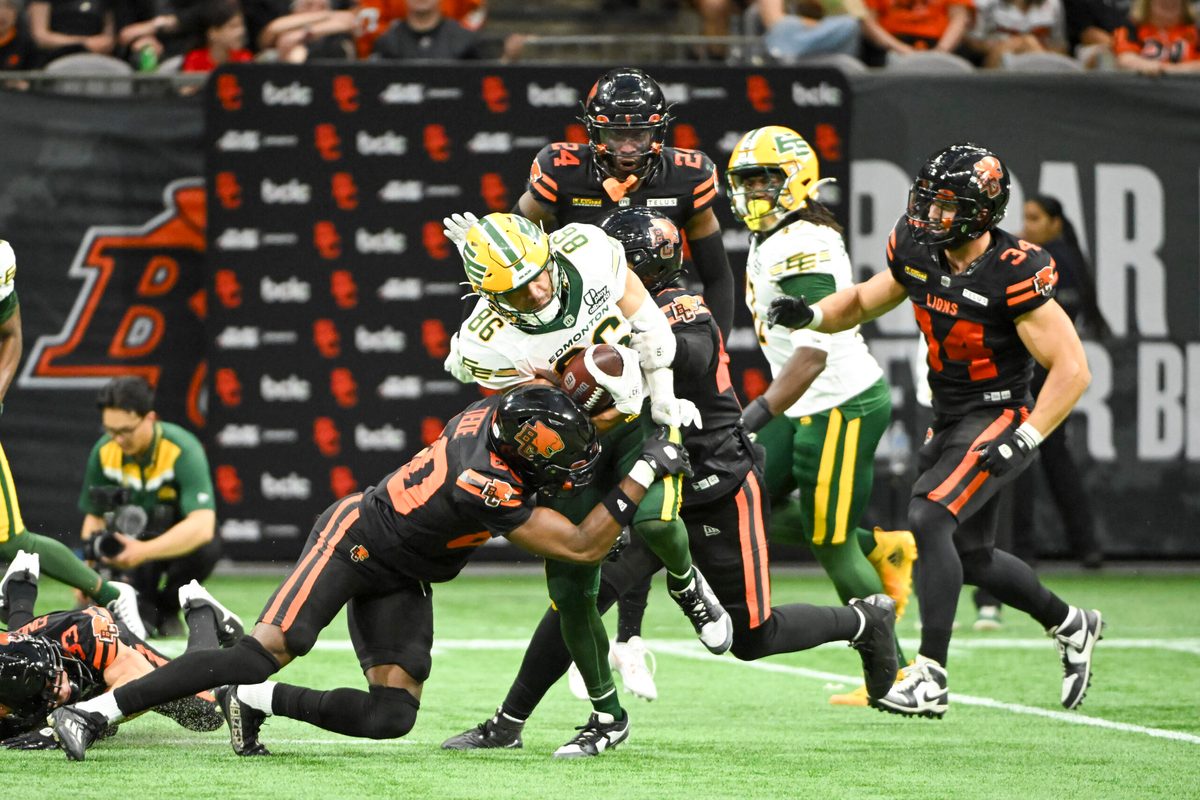 Jun 7, 2025; Vancouver, British Columbia, Canada;  BC Lions wide receiver Ezecheil Tieide (80) tackles Edmonton Elks wide receiver Arkell Smith (86) during the second half at BC Place Stadium. Mandatory Credit: Anne-Marie Sorvin-Imagn Images