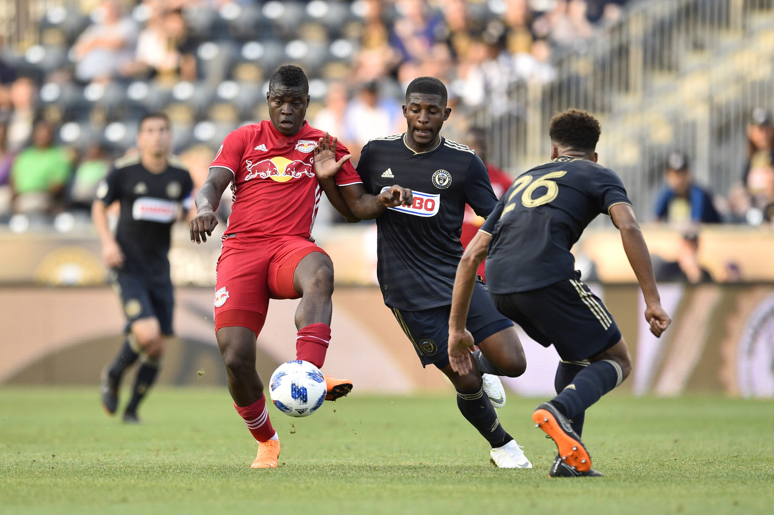 Jun 16, 2018; Philadelphia, PA, USA; New York Red Bulls forward Carlos Rivas (left) plays the ball against Philadelphia Union defender Mark McKenzie (middle) and defender Auston Trusty (26) during the first half at Talen Energy Stadium. Mandatory Credit: Derik Hamilton-Imagn Images