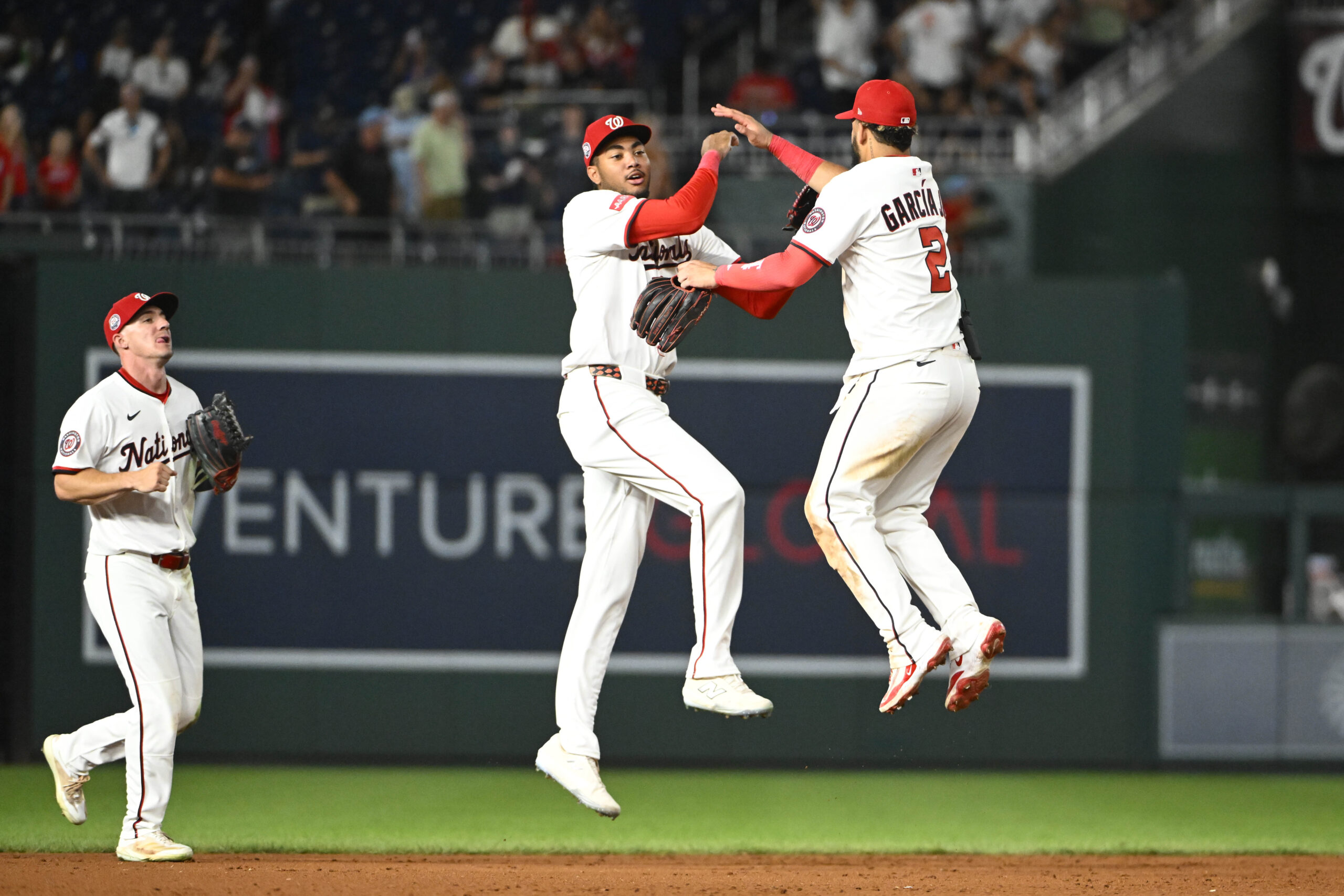 Jul 22, 2025; Washington, District of Columbia, USA; Washington Nationals left fielder James Wood (29) celebrates with  second baseman Luis Garcia Jr. (2) as center fielder Jacob Young (30) looks on after the game against the Cincinnati Reds at Nationals Park. Mandatory Credit: Brad Mills-Imagn Images
