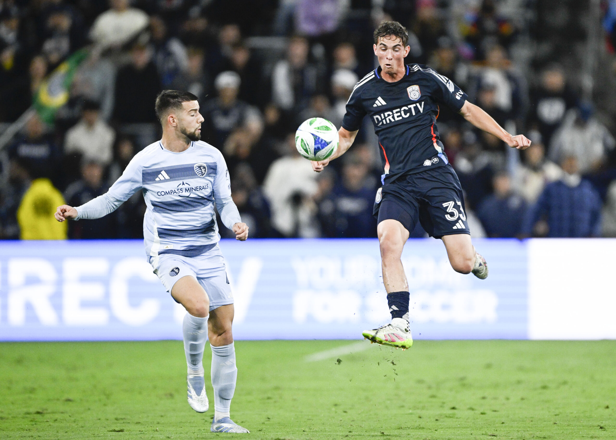 May 17, 2025; San Diego, California, USA; San Diego FC defender Oscar Verhoeven (33) fights for the ball with Sporting Kansas City defender Robert Voloder (4) during the first half  at Snapdragon Stadium. Mandatory Credit: Denis Poroy-Imagn Images