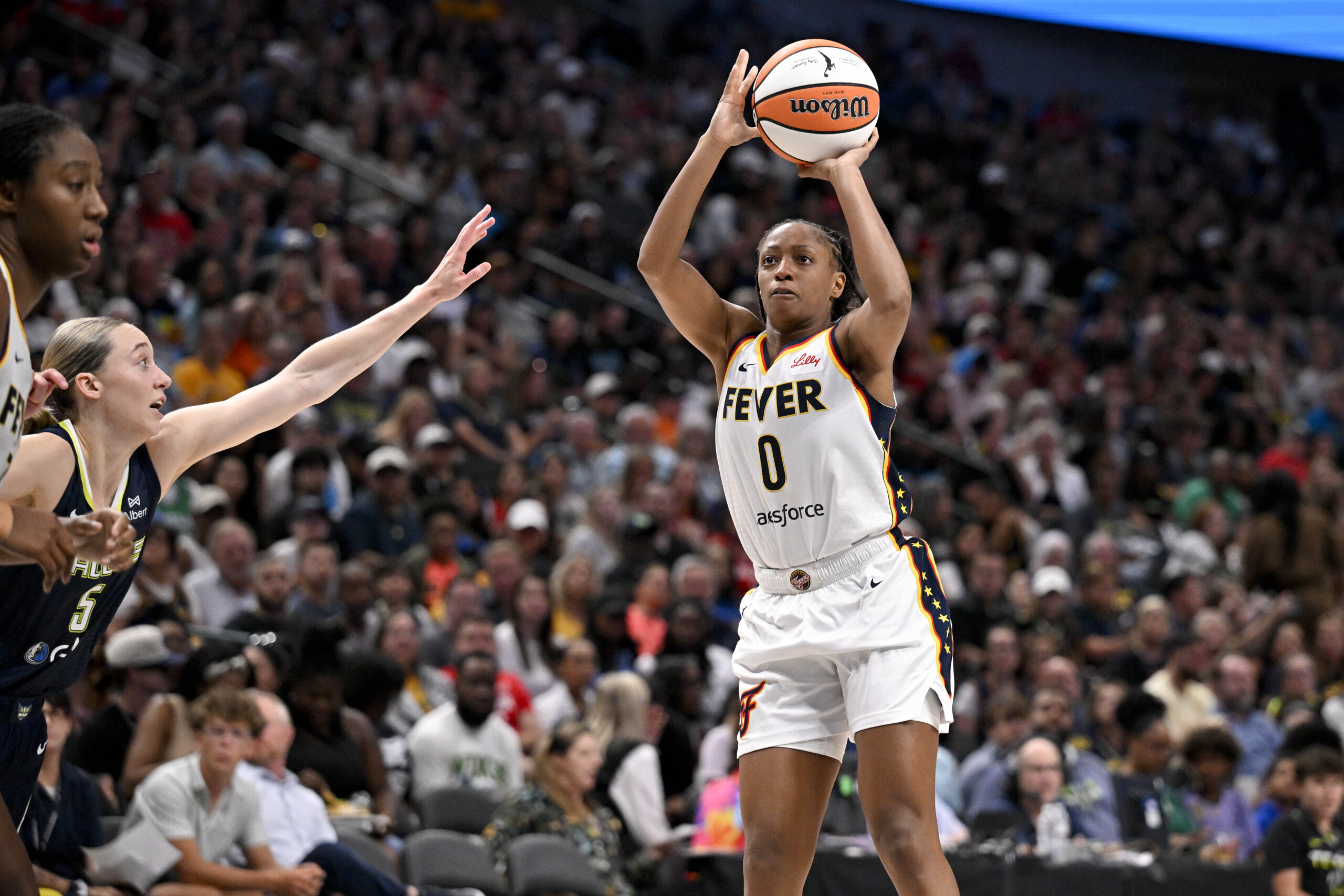 Aug 1, 2025; Dallas, Texas, USA; Indiana Fever guard Kelsey Mitchell (0) makes a jump shot over Dallas Wings guard Paige Bueckers (5) during the second half at the American Airlines Center. Mandatory Credit: Jerome Miron-Imagn Images