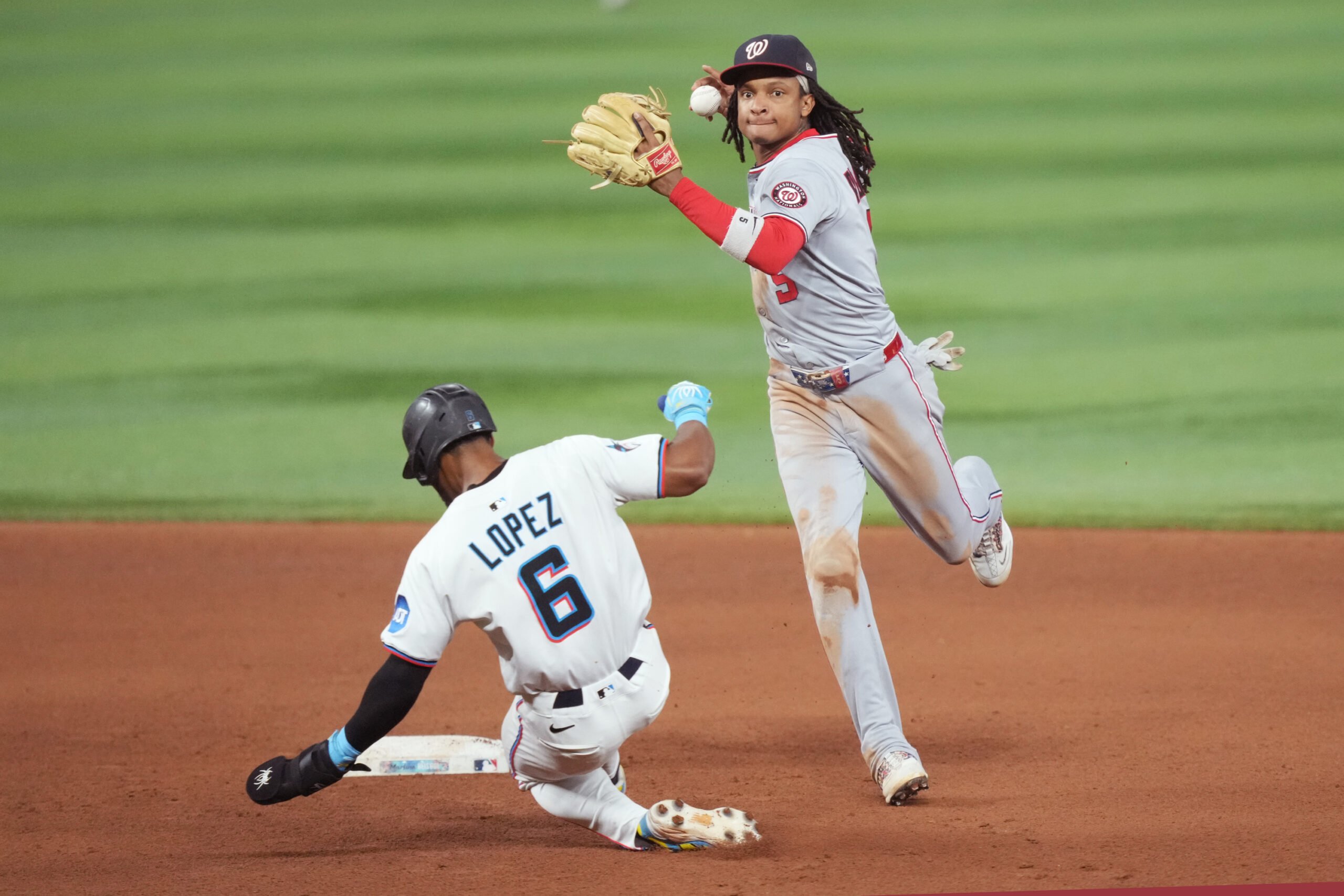 Sep 9, 2025; Miami, Florida, USA; Washington Nationals shortstop CJ Abrams (5) completes a double play after getting the force out of Miami Marlins shortstop Otto Lopez (6) at second base in the seventh inning at loanDepot Park. Mandatory Credit: Jim Rassol-Imagn Images