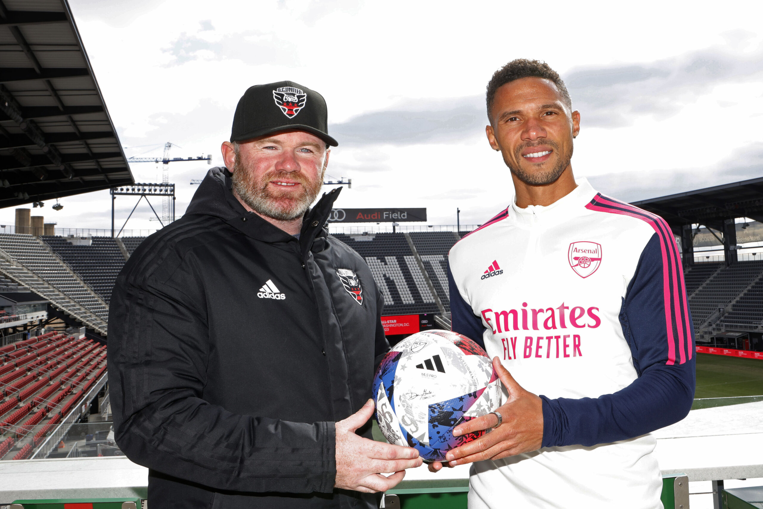 Mar 14, 2023; Washington, DC, USA; D.C. United head coach Wayne Rooney (L) and current on-air talent for Inter Miami Kieran Gibbs (R) hold an official MLS game ball on the Audi Field rooftop during an announcement that Premier League club Arsenal will play the MLS All Stars at the MLS All-Star Game in Washington D.C at Audi Field. Mandatory Credit: Geoff Burke-Imagn Images
