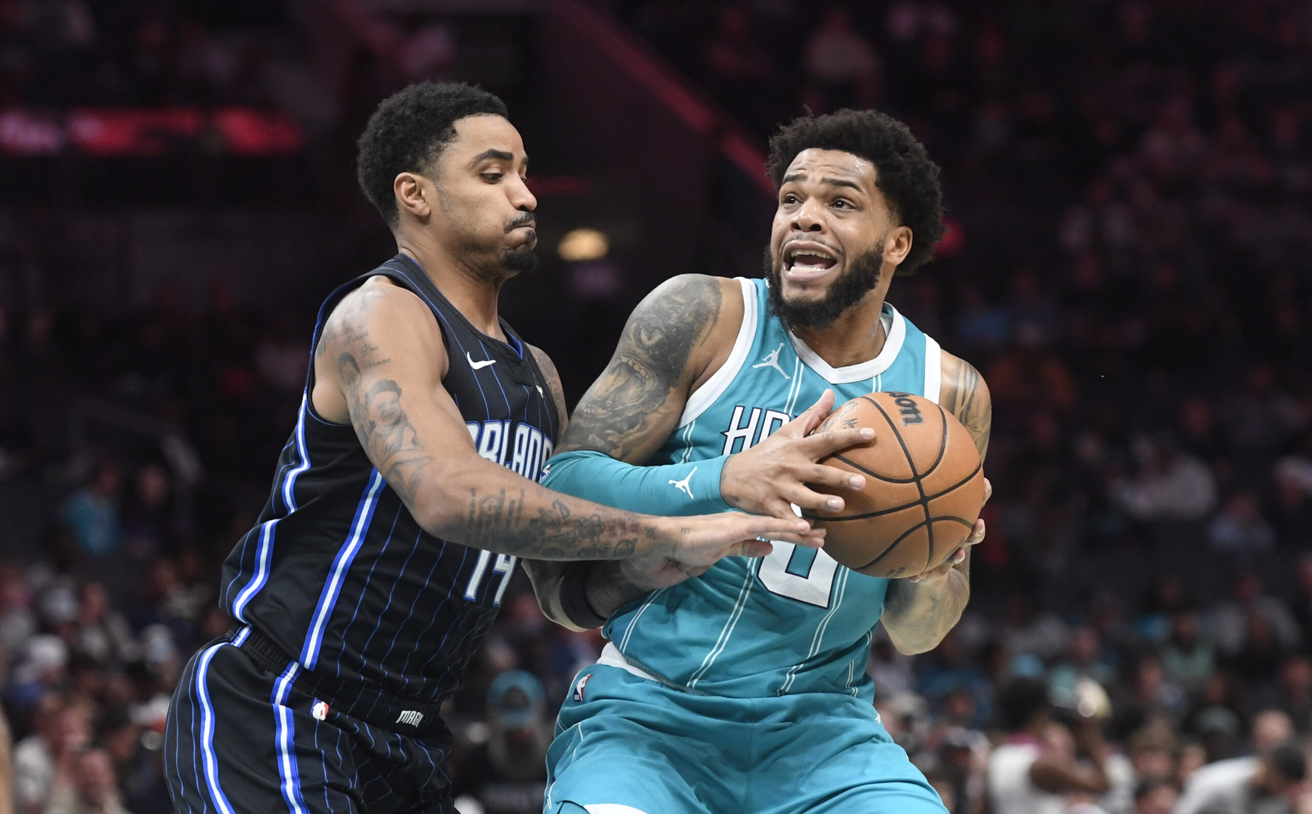 Mar 25, 2025; Charlotte, North Carolina, USA;  Charlotte Hornets forward Miles Bridges (0) looks to pass as he is defended by Orlando Magic guard Gary Harris (14) during the second half at the Spectrum Center. Mandatory Credit: Sam Sharpe-Imagn Images