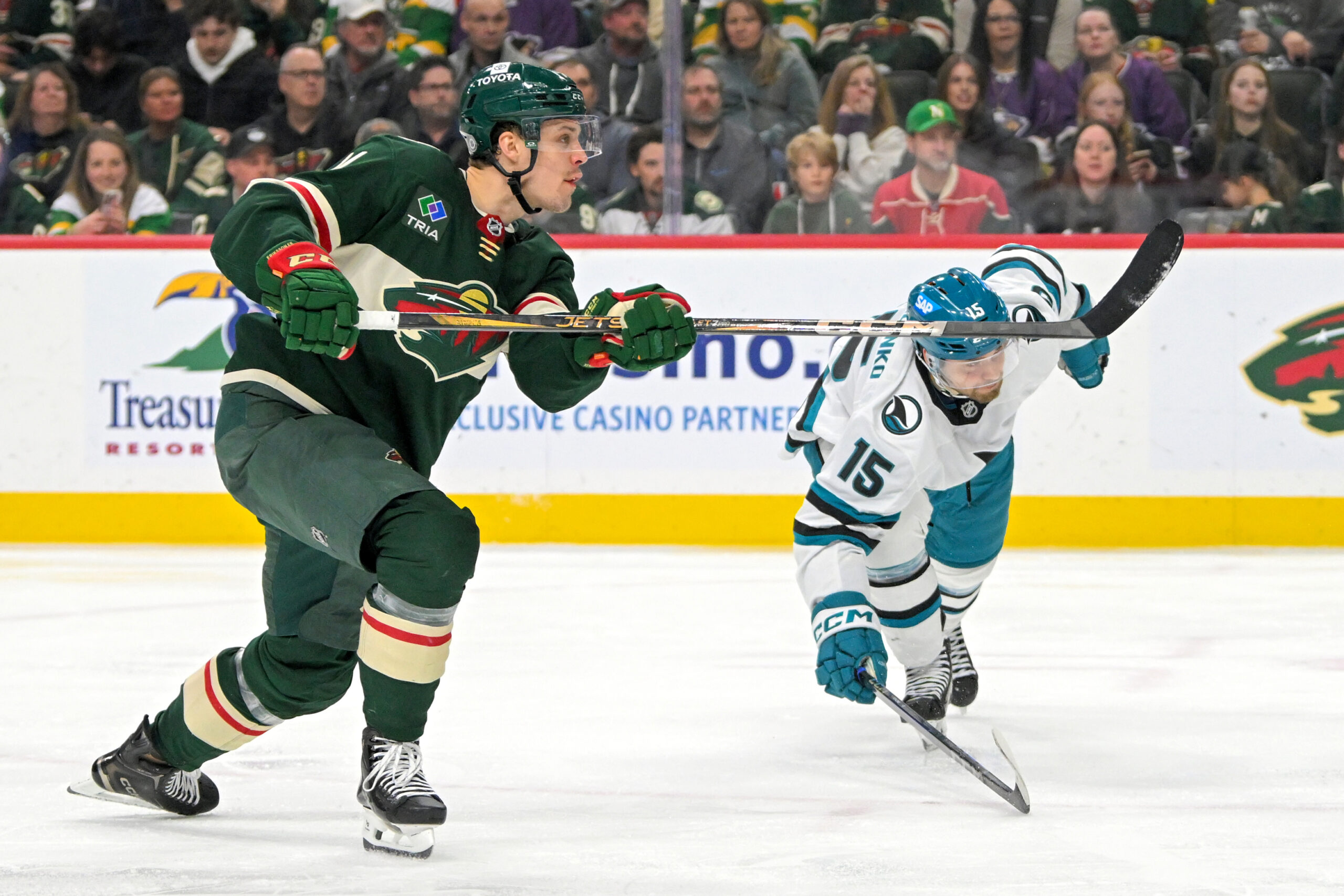 Apr 9, 2025; Saint Paul, Minnesota, USA;  Minnesota Wild forward Joel Eriksson Ek (14) scores his fourth goal of the night as San Jose Sharks forward Nikolai Kovalenko (15) defends during the third period at Xcel Energy Center. Mandatory Credit: Nick Wosika-Imagn Images