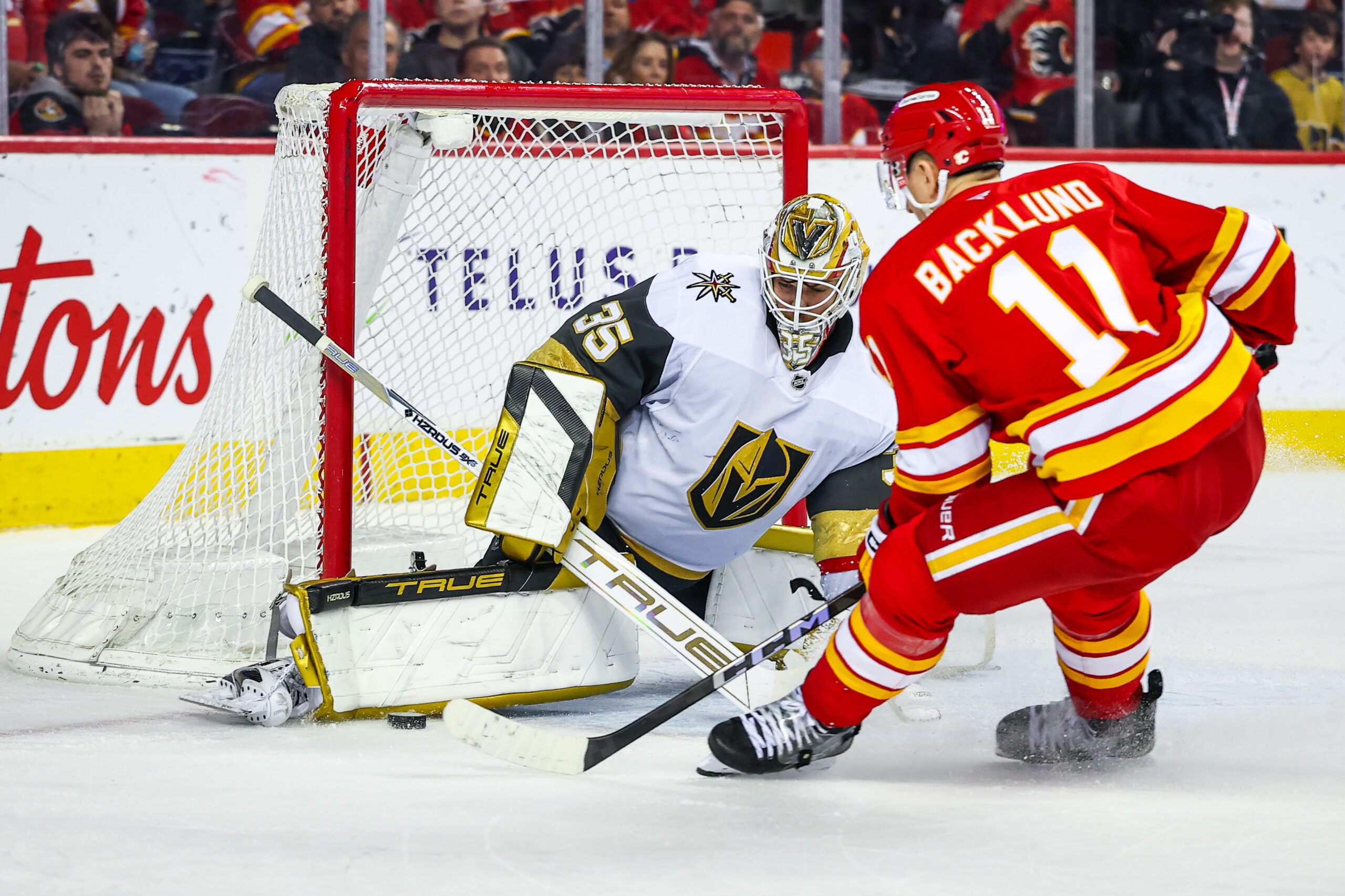 Apr 15, 2025; Calgary, Alberta, CAN; Vegas Golden Knights goaltender Ilya Samsonov (35) makes a save against Calgary Flames center Mikael Backlund (11) during the overtime period at Scotiabank Saddledome. Mandatory Credit: Sergei Belski-Imagn Images