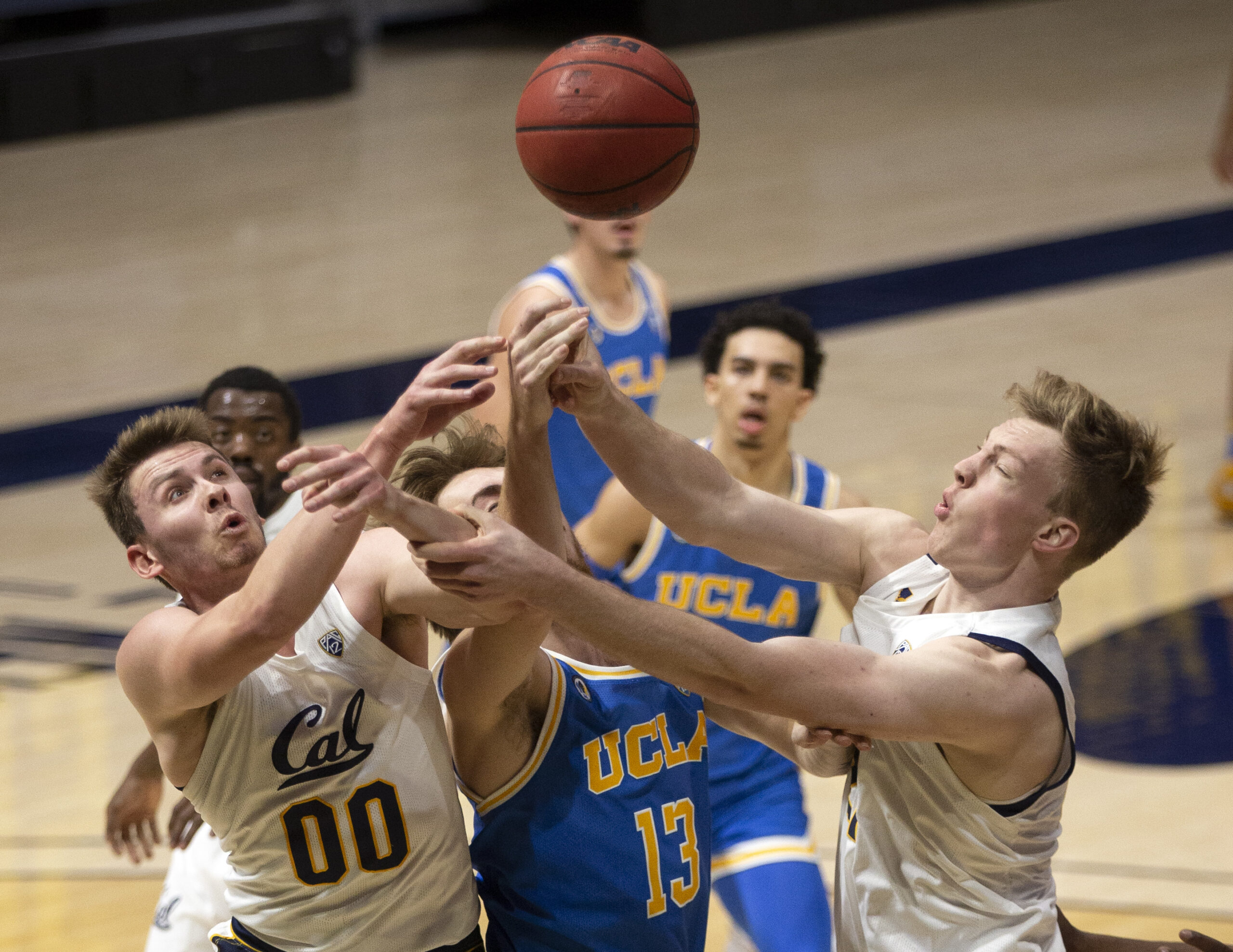 Jan 21, 2021; Berkeley, California, USA; UCLA Bruins guard Jake Kyman (13) vies for a rebound with California Golden Bears defenders Ryan Betley (00) and Lars Thiemann (21) during the first half of an NCAA men s college basketball game at Haas Pavilion. Mandatory Credit: D. Ross Cameron-Imagn Images