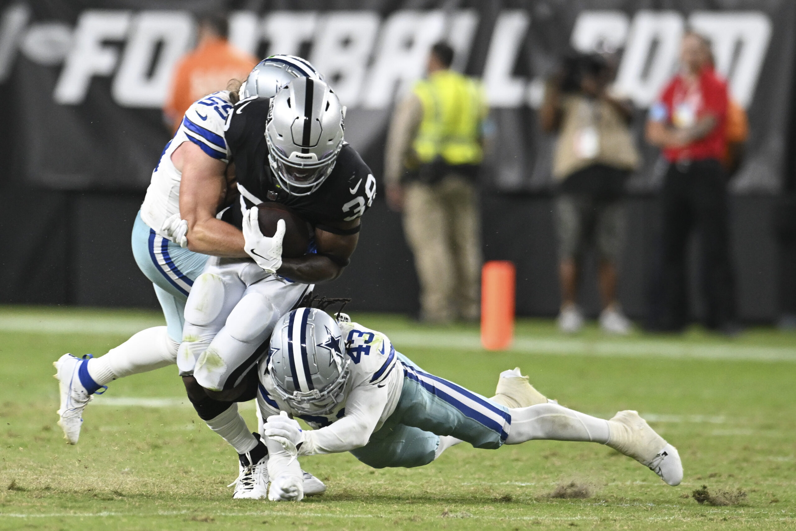 Aug 17, 2024; Paradise, Nevada, USA; Las Vegas Raiders running back Brittain Brown (38) is tackled by Dallas Cowboys linebacker Willie Harvey Jr. (55) and cornerback Kemon Hall (43) in the fourth quarter at Allegiant Stadium. Mandatory Credit: Candice Ward-Imagn Images