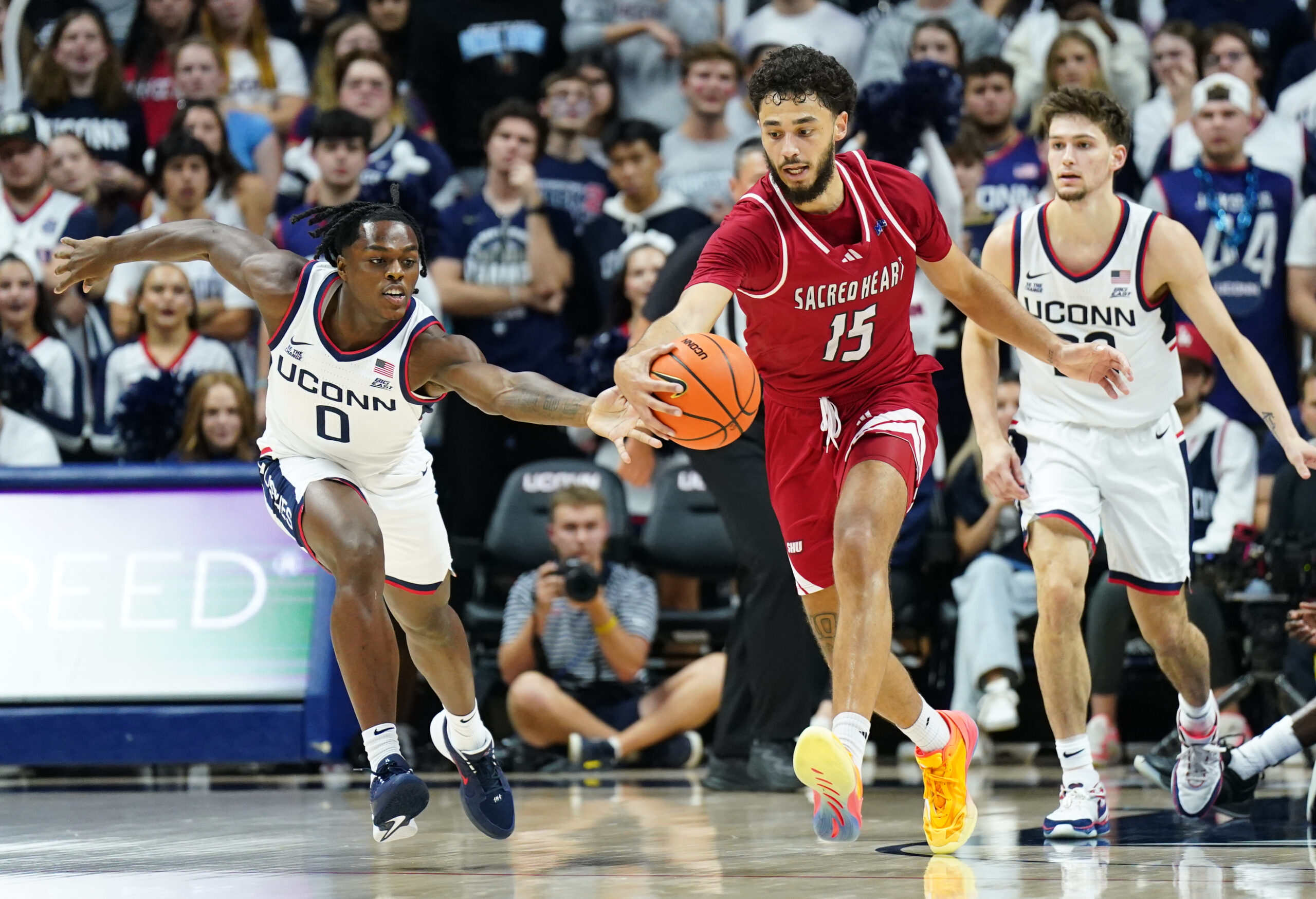 Nov 6, 2024; Storrs, Connecticut, USA;Connecticut Huskies guard Ahmad Nowell (0) and Sacred Heart Pioneers forward Raymond Espinal-Guzman (15) work for the ball in the second half at Harry A. Gampel Pavilion. Mandatory Credit: David Butler II-Imagn Images