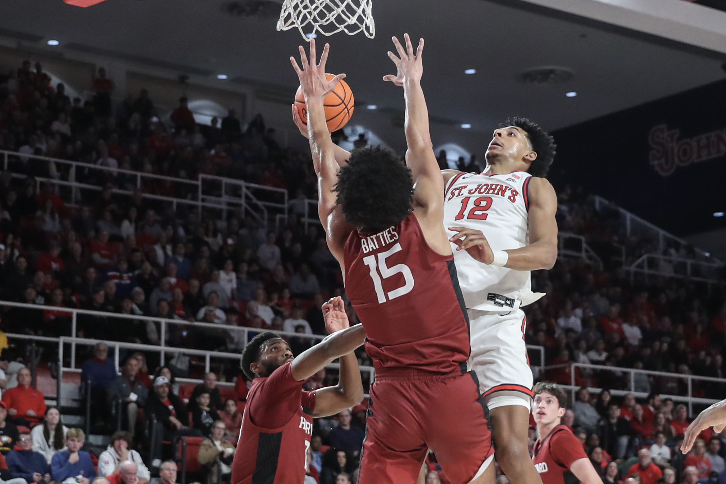 Nov 30, 2024; Queens, New York, USA; St. John's Red Storm guard RJ Luis Jr. (12) drives past Harvard Crimson forward Thomas Batties II (15) in the second half at Carnesecca Arena. Mandatory Credit: Wendell Cruz-Imagn Images