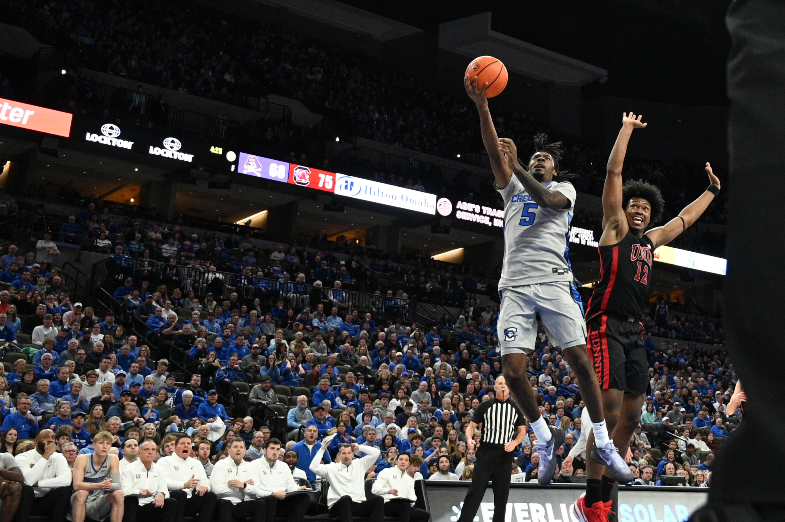 Dec 7, 2024; Omaha, Nebraska, USA;  Creighton Bluejays guard Jamiya Neal (5) scores against UNLV Rebels forward Jacob Bannarbie (12) in the second half at CHI Health Center Omaha. Mandatory Credit: Steven Branscombe-Imagn Images