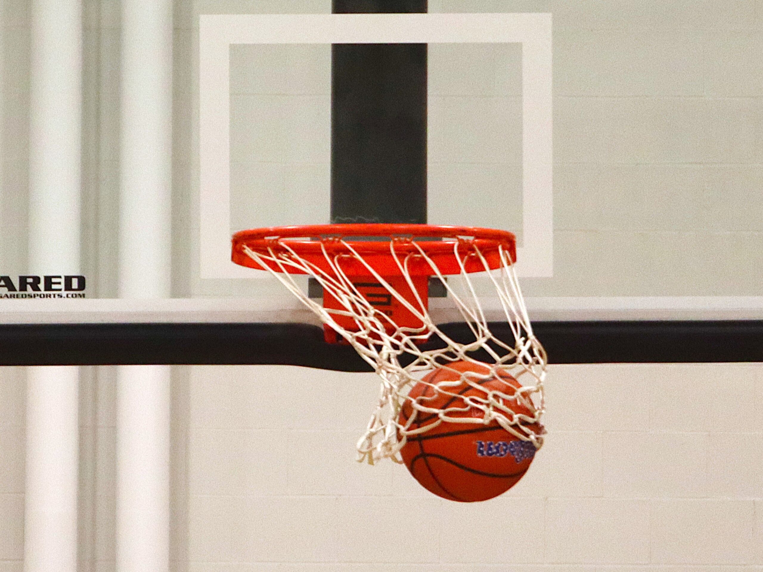 A basketball swishes the net as it goes through the hoop.