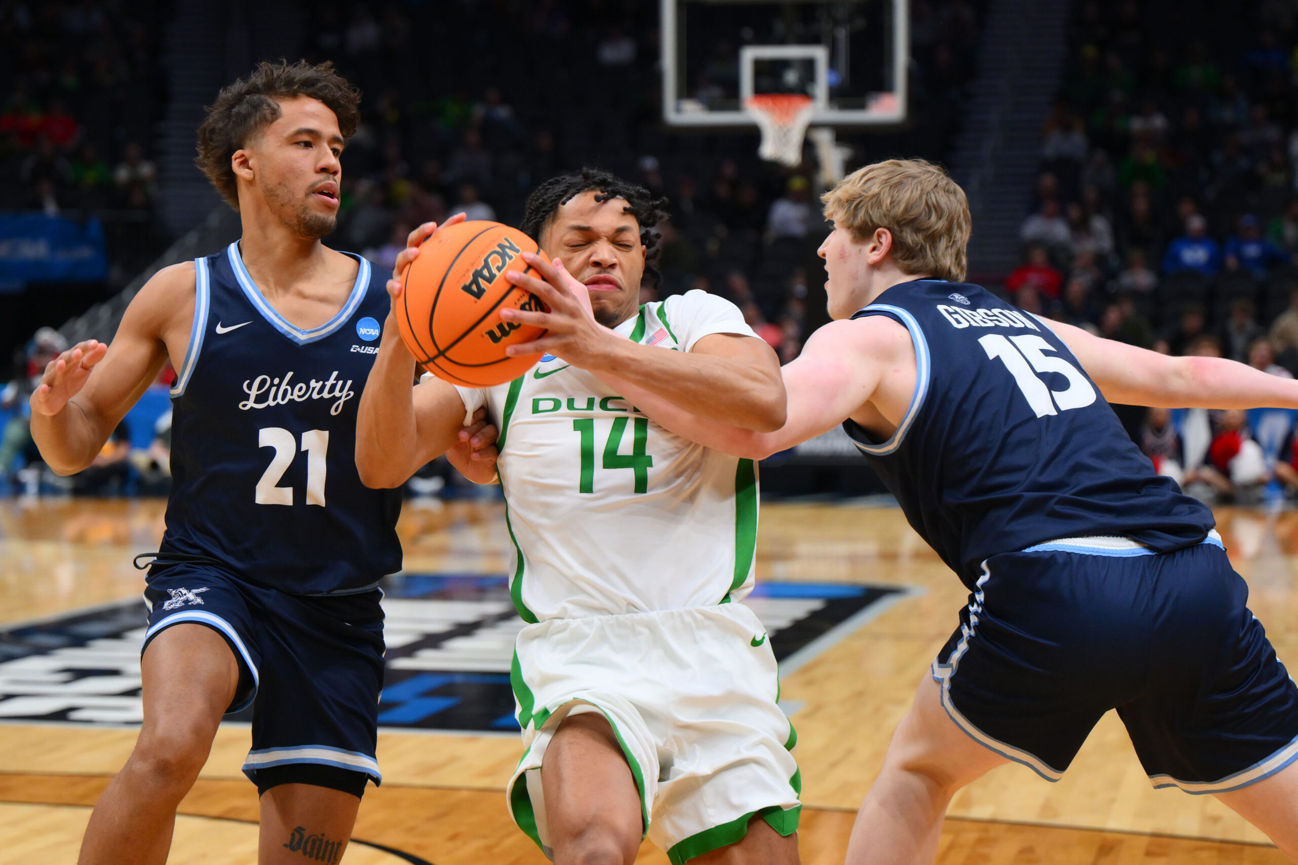 Mar 21, 2025; Seattle, WA, USA; Oregon Ducks guard Jayson Williams-Johnson (14) dribbles the ball past Liberty Flames guard Gabriel McKay (21) during the second half in the first round of the NCAA Tournament at Climate Pledge Arena. Mandatory Credit: Steven Bisig-Imagn Images