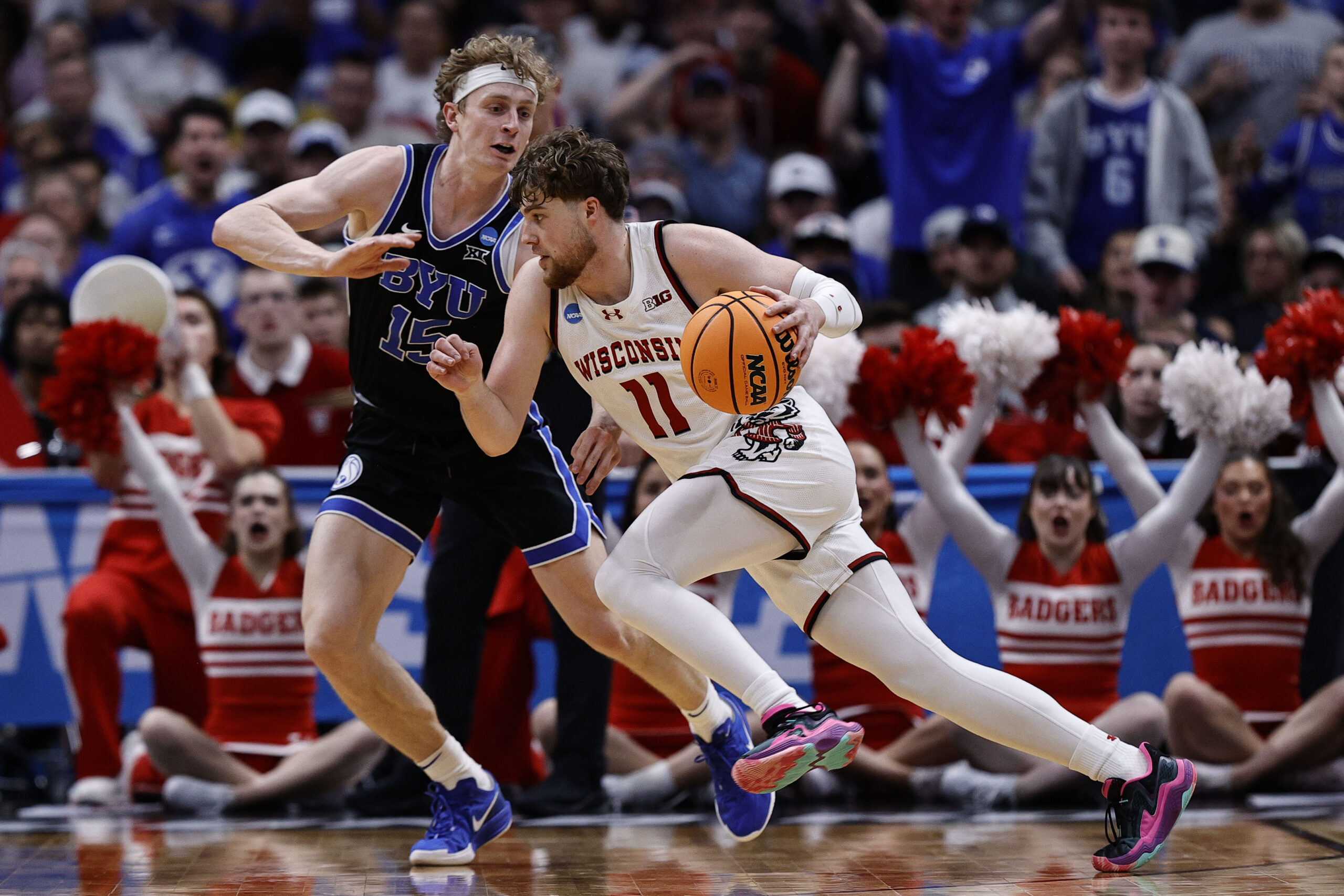 Mar 22, 2025; Denver, CO, USA; Wisconsin Badgers guard Max Klesmit (11) dribbles the ball past Brigham Young Cougars forward Richie Saunders (15) during the second half in the second round of the NCAA Tournament  at Ball Arena. Mandatory Credit: Isaiah J. Downing-Imagn Images